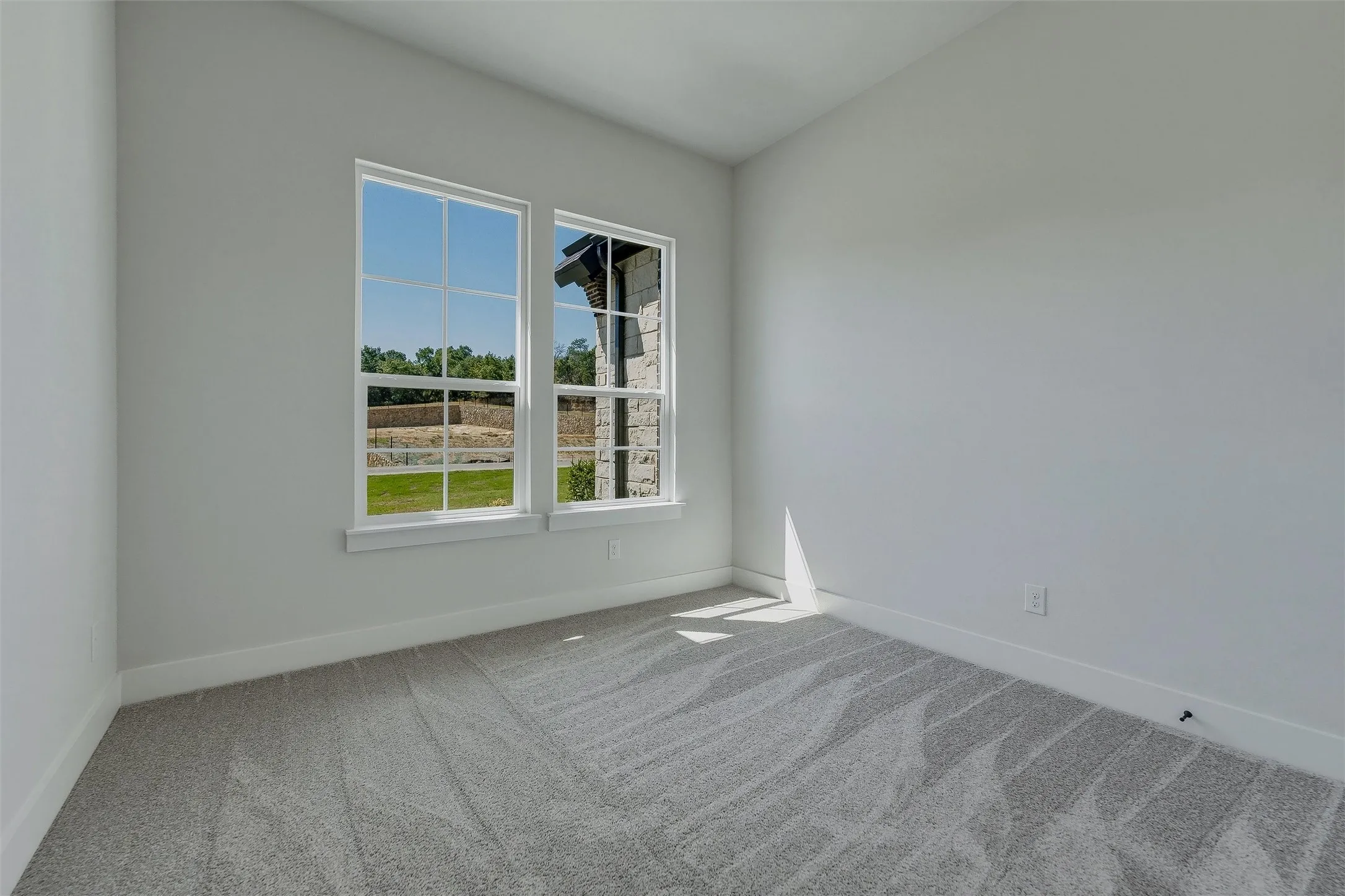 Twin windows with white frames, light gray wall paint, and gray patterned carpeting
