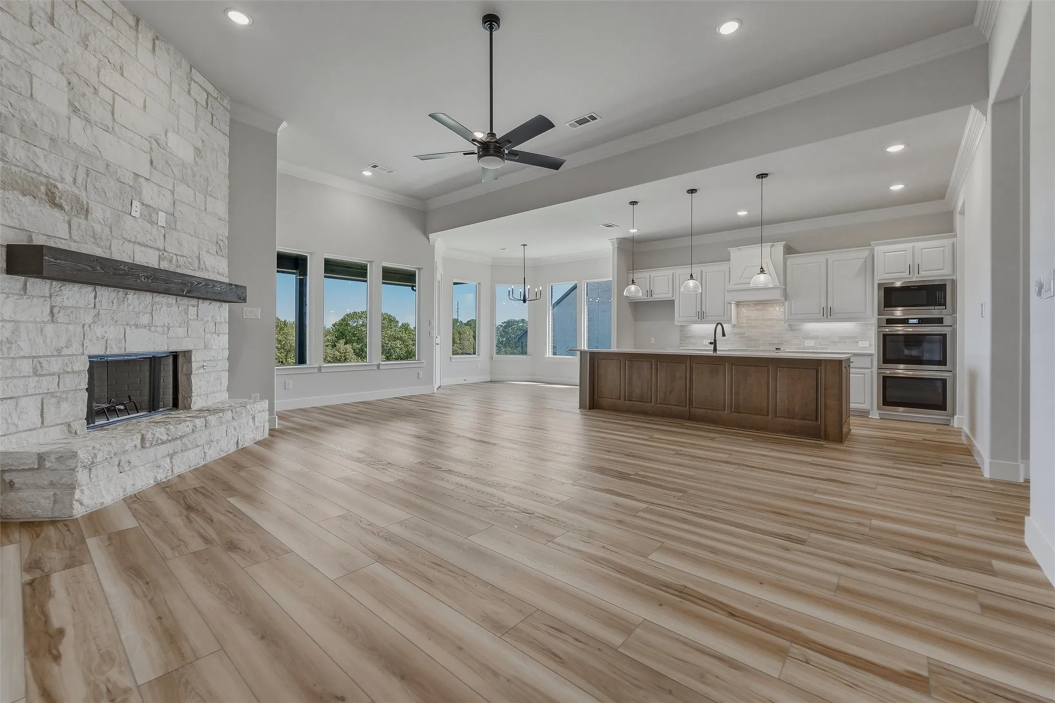 Spacious interior featuring wood-finish flooring, a stone fireplace with a dark wood mantle, and large windows