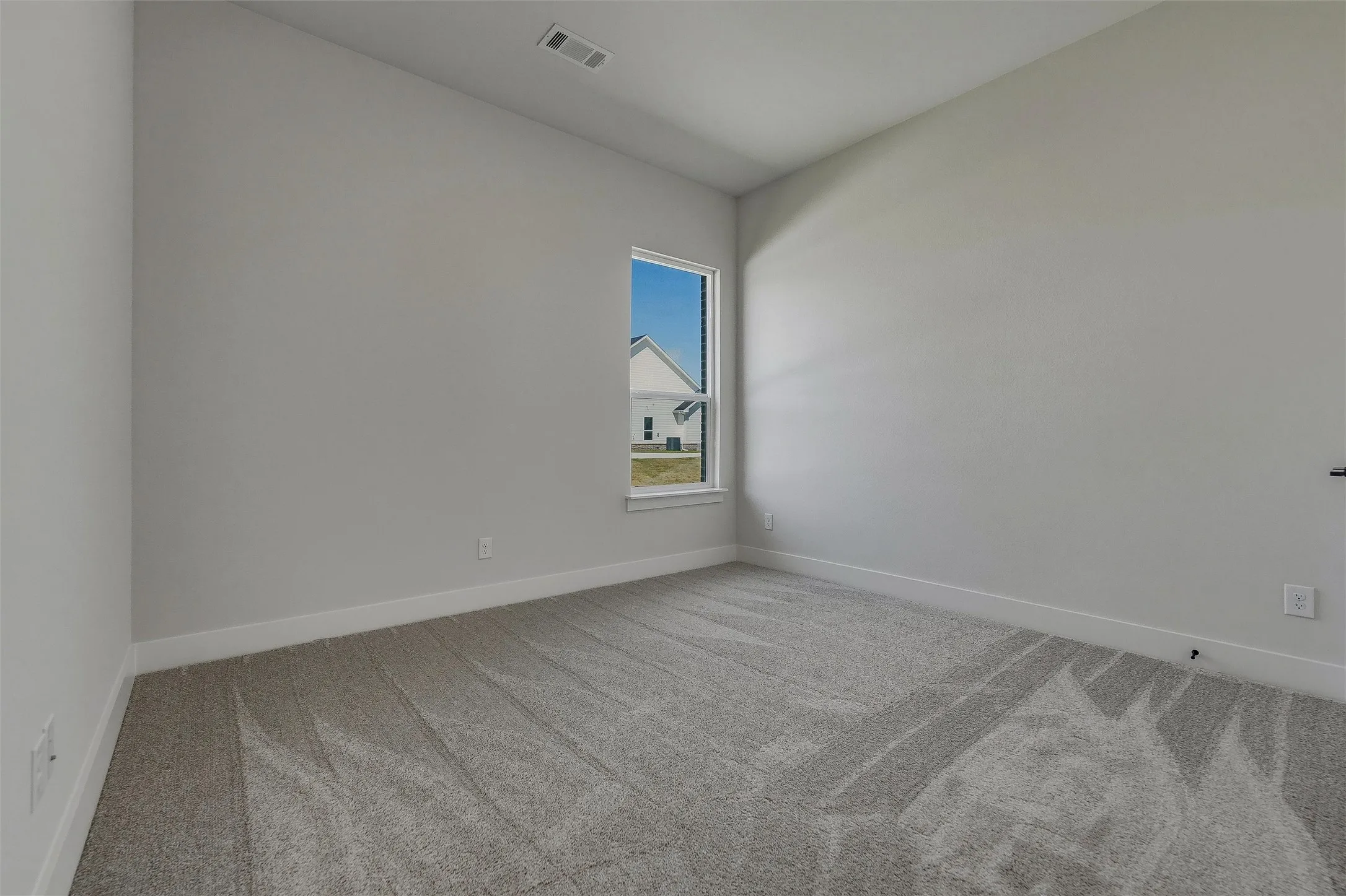 Carpeted room with a single window and light gray walls