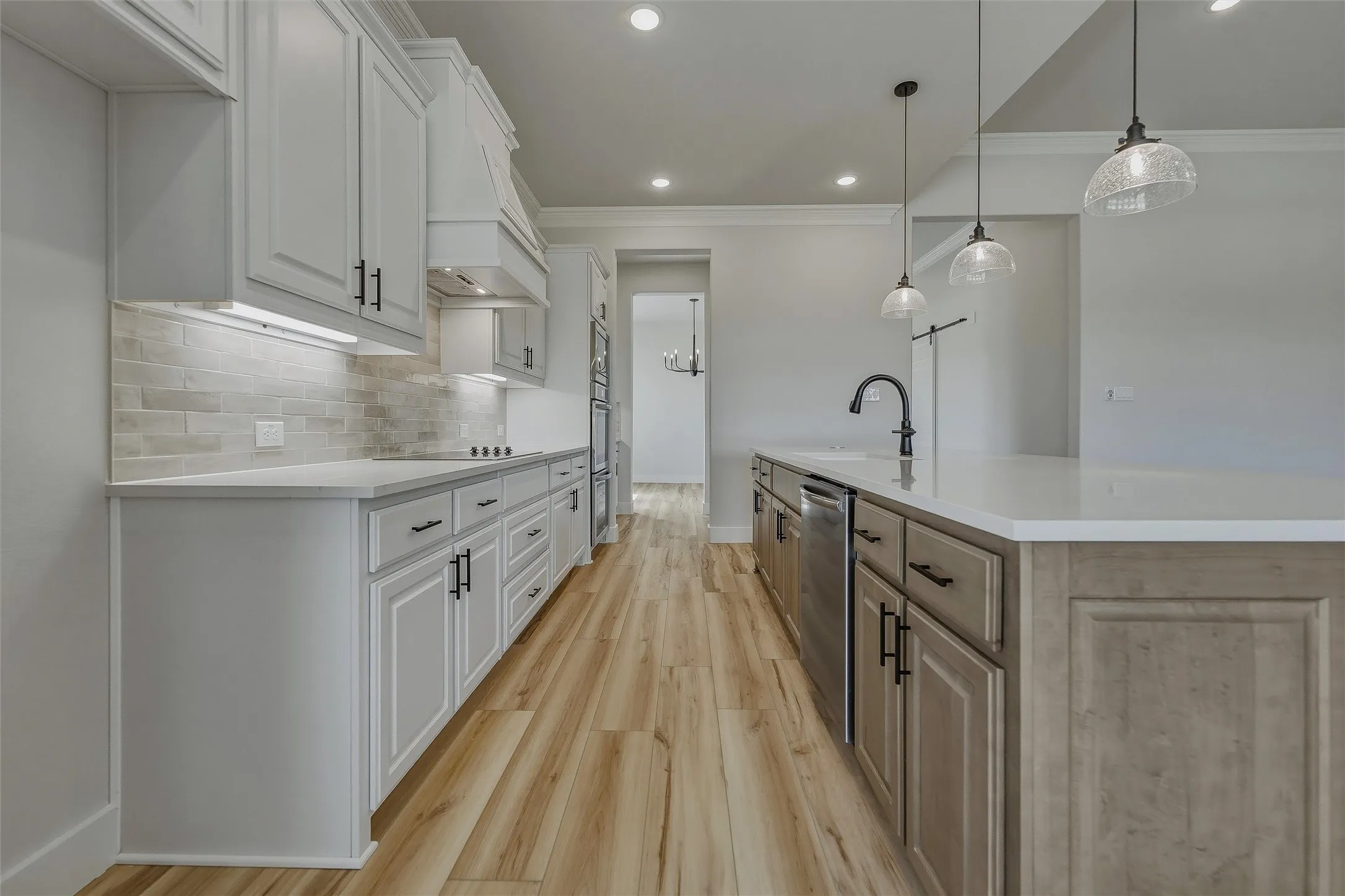 Kitchen featuring white shaker-style cabinetry, a built-in range hood, a subway tile backsplash, and wood-finish flooring
