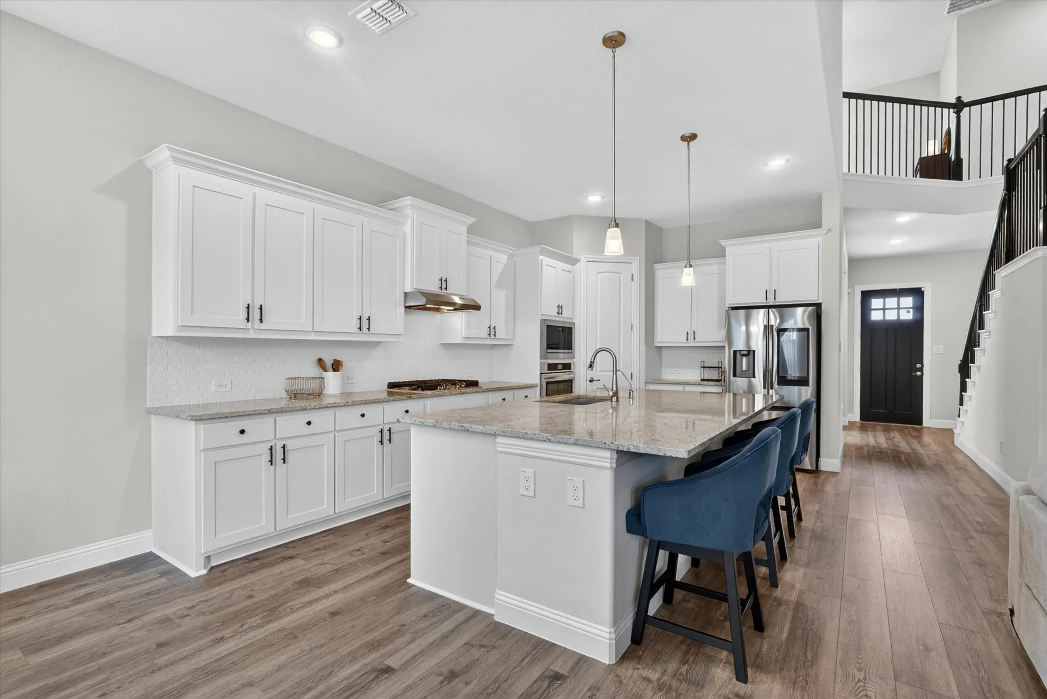 Open-concept kitchen featuring white cabinetry, light-toned countertops, and wood-finish flooring