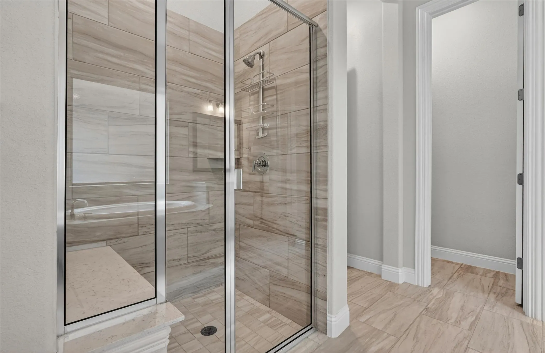 Walk-in shower with clear glass enclosure and chrome fixtures