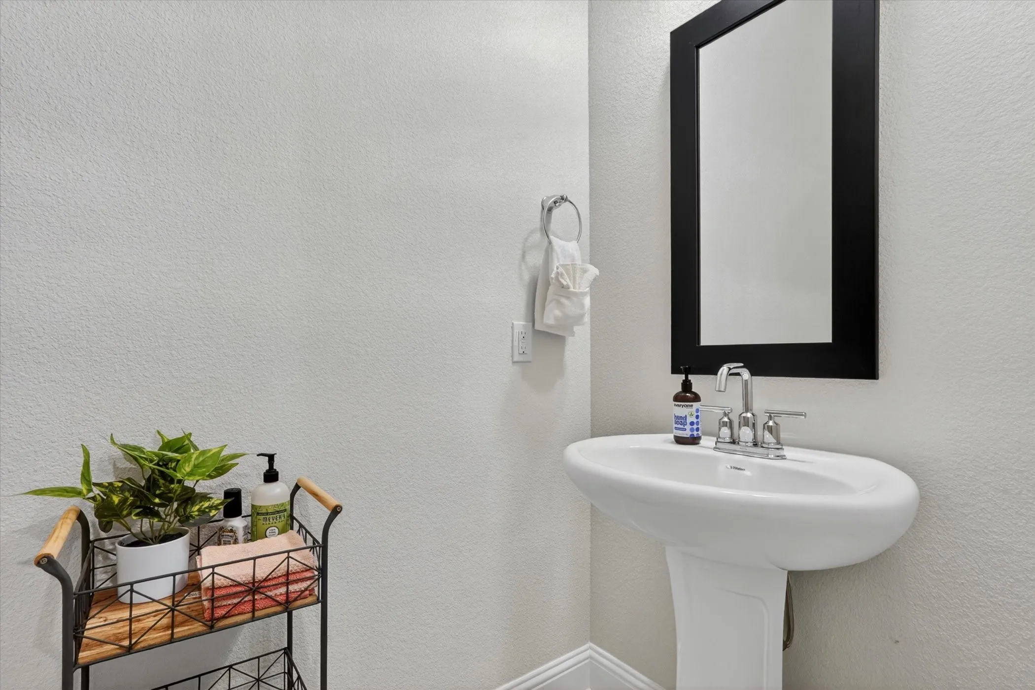 Pedestal sink with chrome faucet and a framed mirror