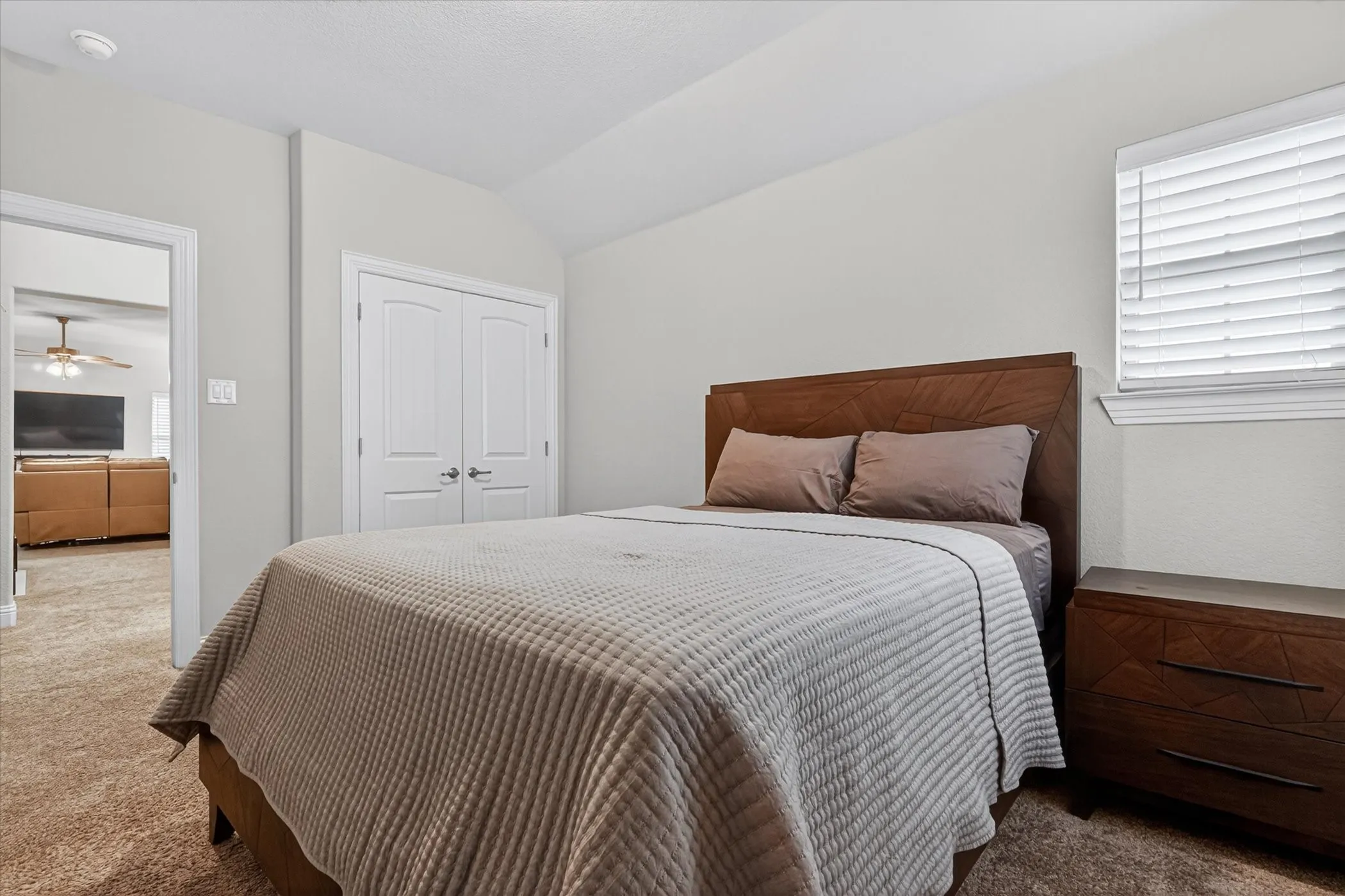 Carpeted room with light neutral wall tones and a window with horizontal blinds