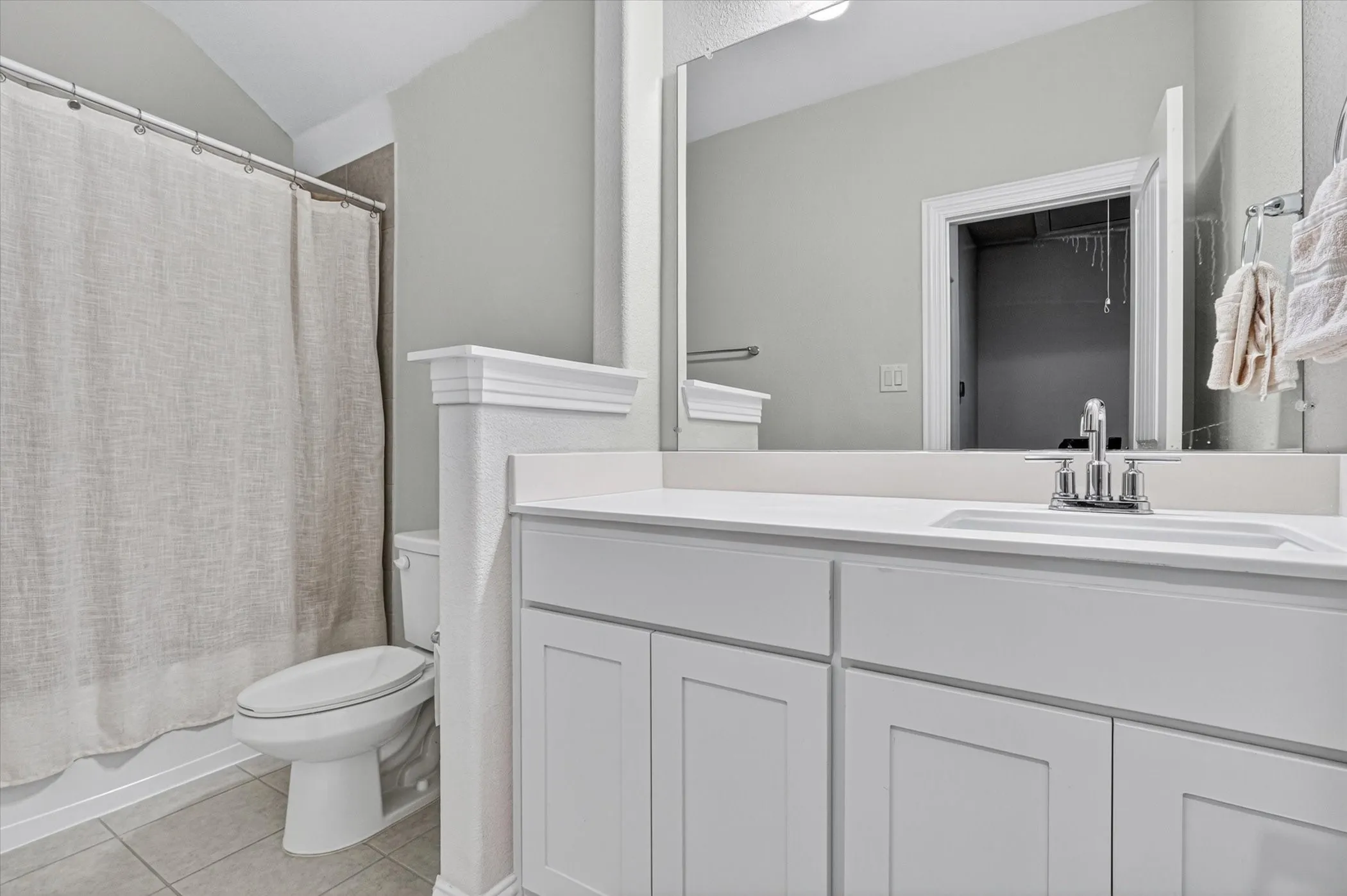 Bathroom featuring a white vanity with an integrated sink, chrome faucet, and expansive mirror