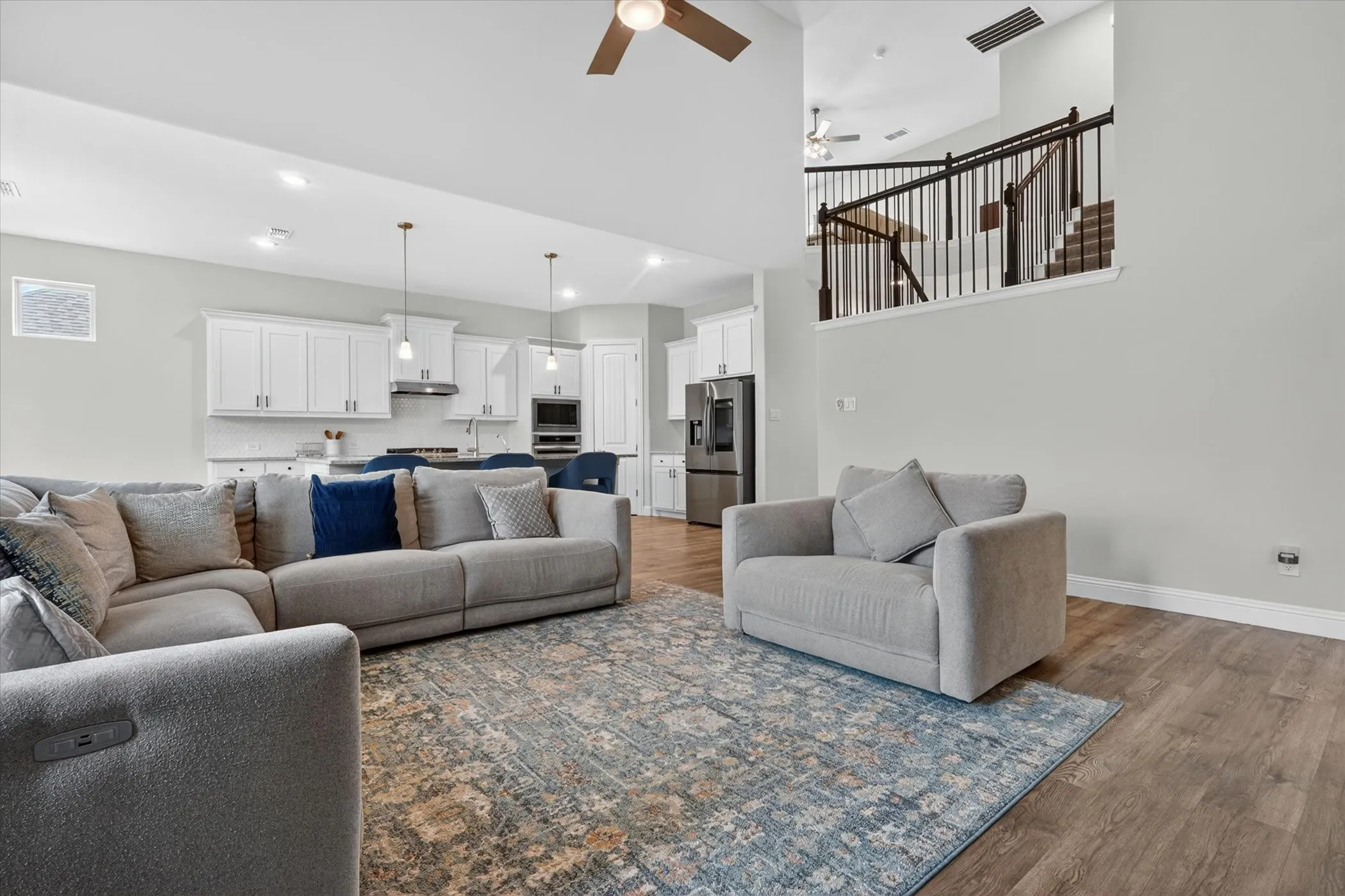 Spacious living area featuring wood-finish flooring, recessed lighting, and a two-story ceiling