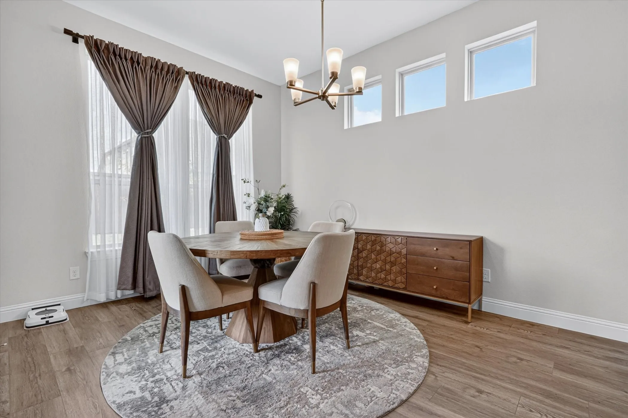 Dining area featuring wood-finish flooring, a contemporary chandelier, and high transom windows
