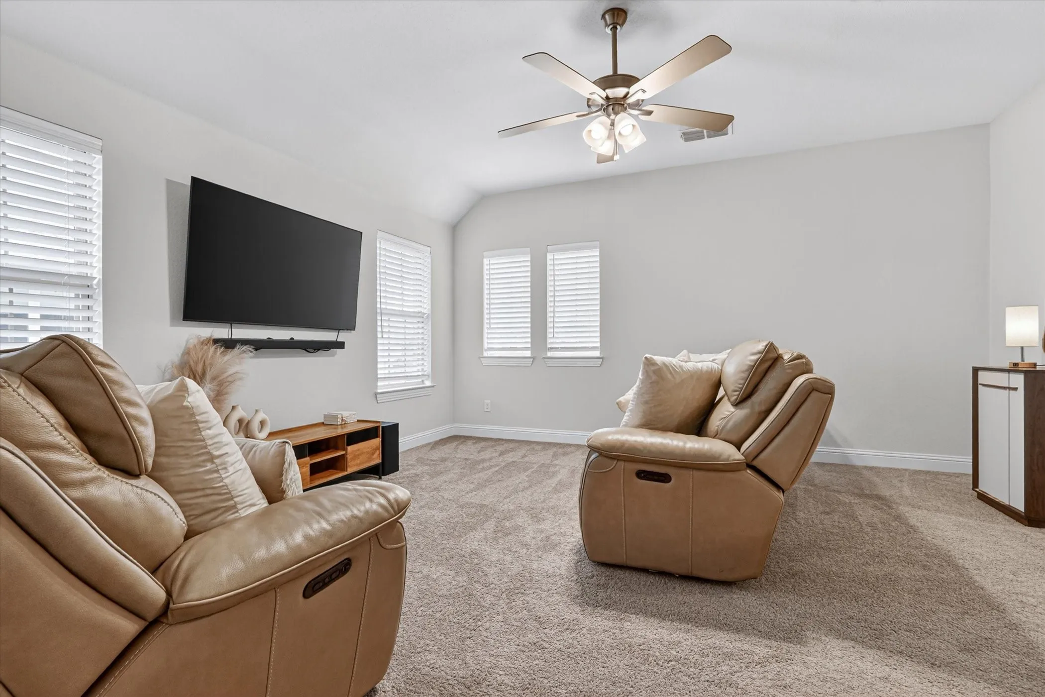 Carpeted room featuring a vaulted ceiling and a ceiling fan with integrated lighting