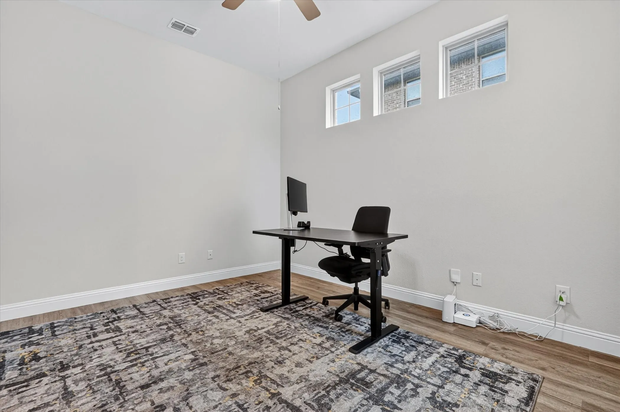 Room with wood-finish flooring, light grey painted walls, and white baseboards