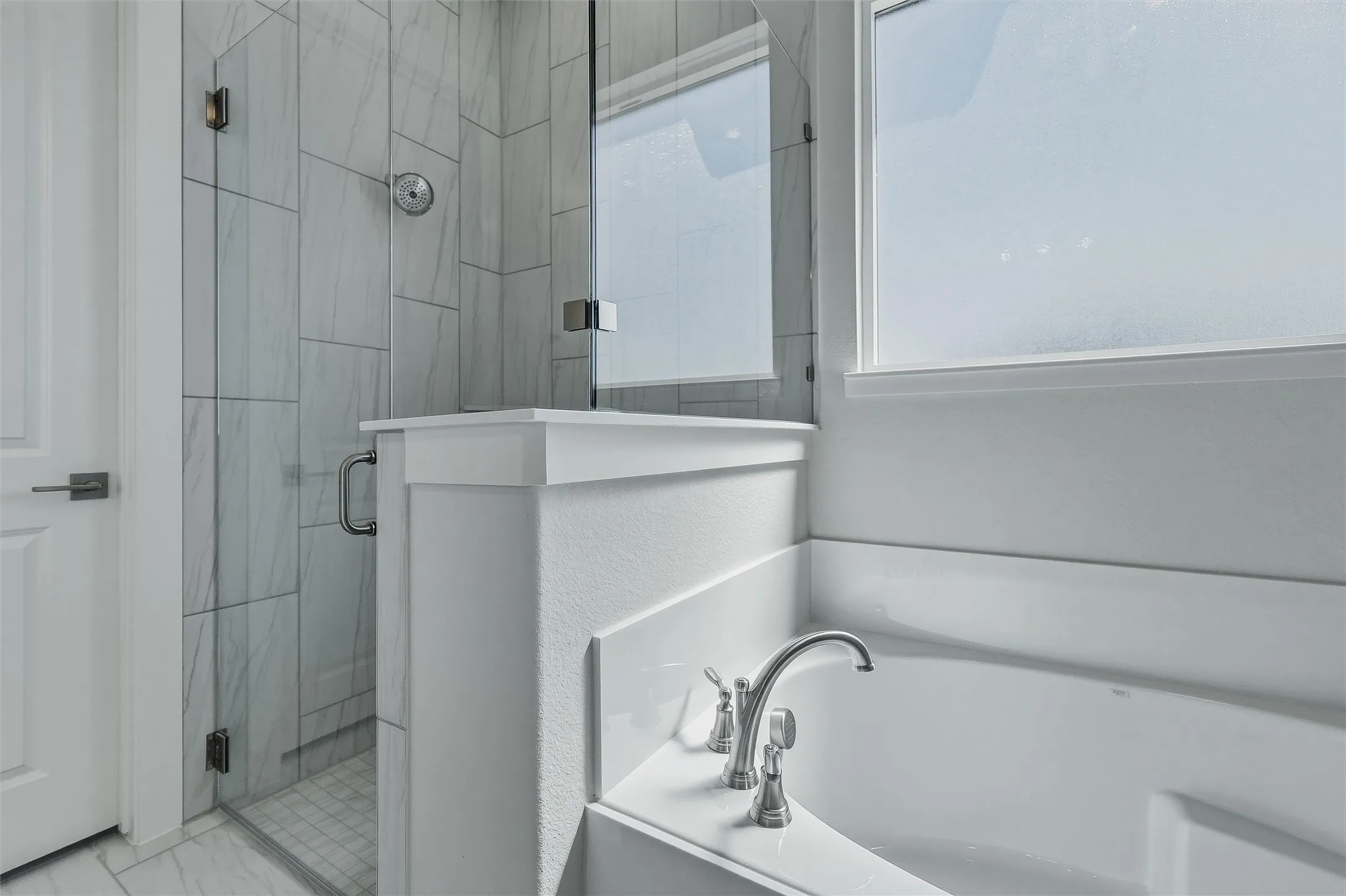Built-in soaking tub with brushed nickel fixtures, a glass-enclosed shower with tile surround, and a frosted window