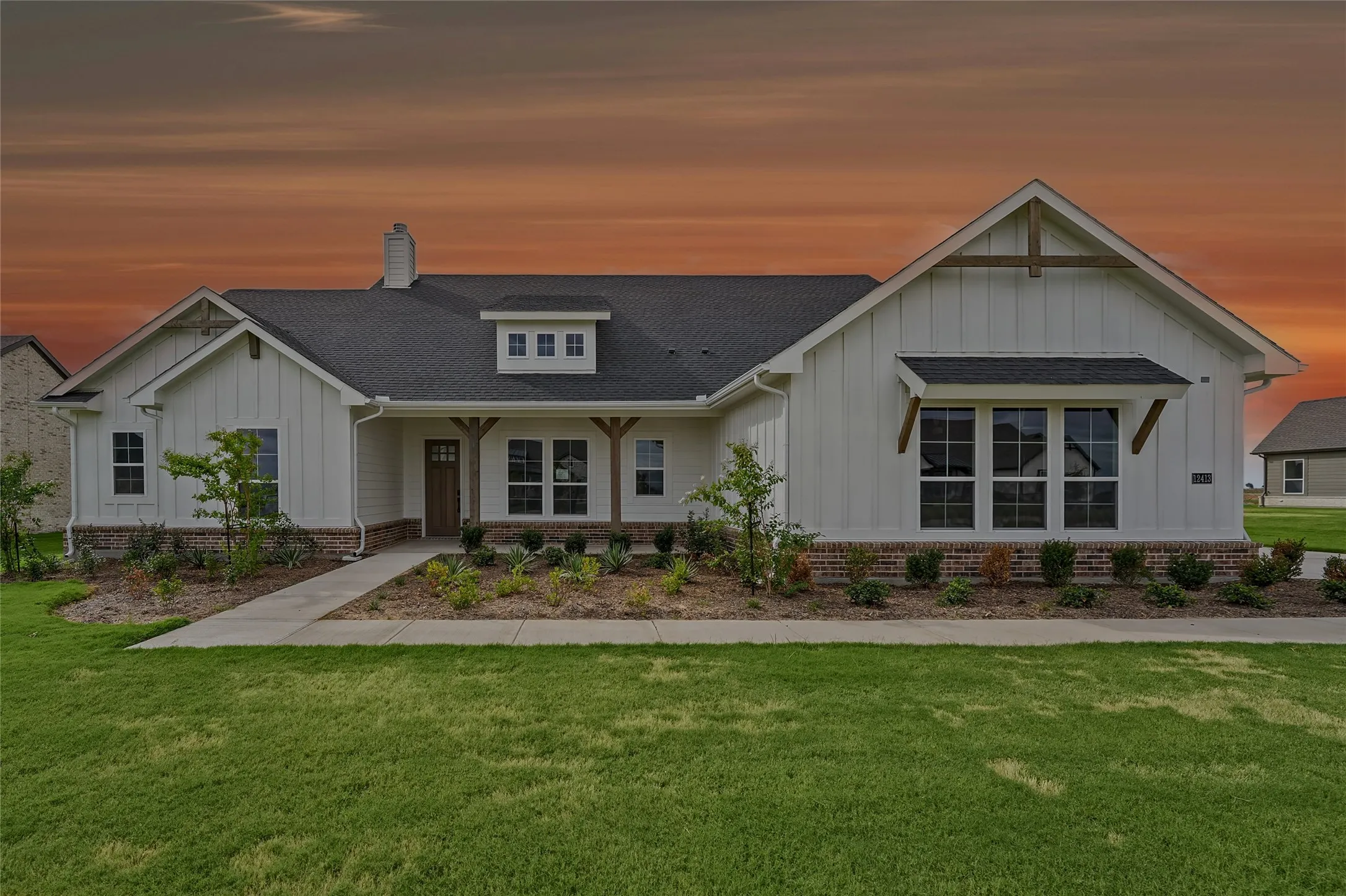 Craftsman-style exterior featuring white vertical siding, dark shingle roof, brick skirting, and an attached front porch with wood columns