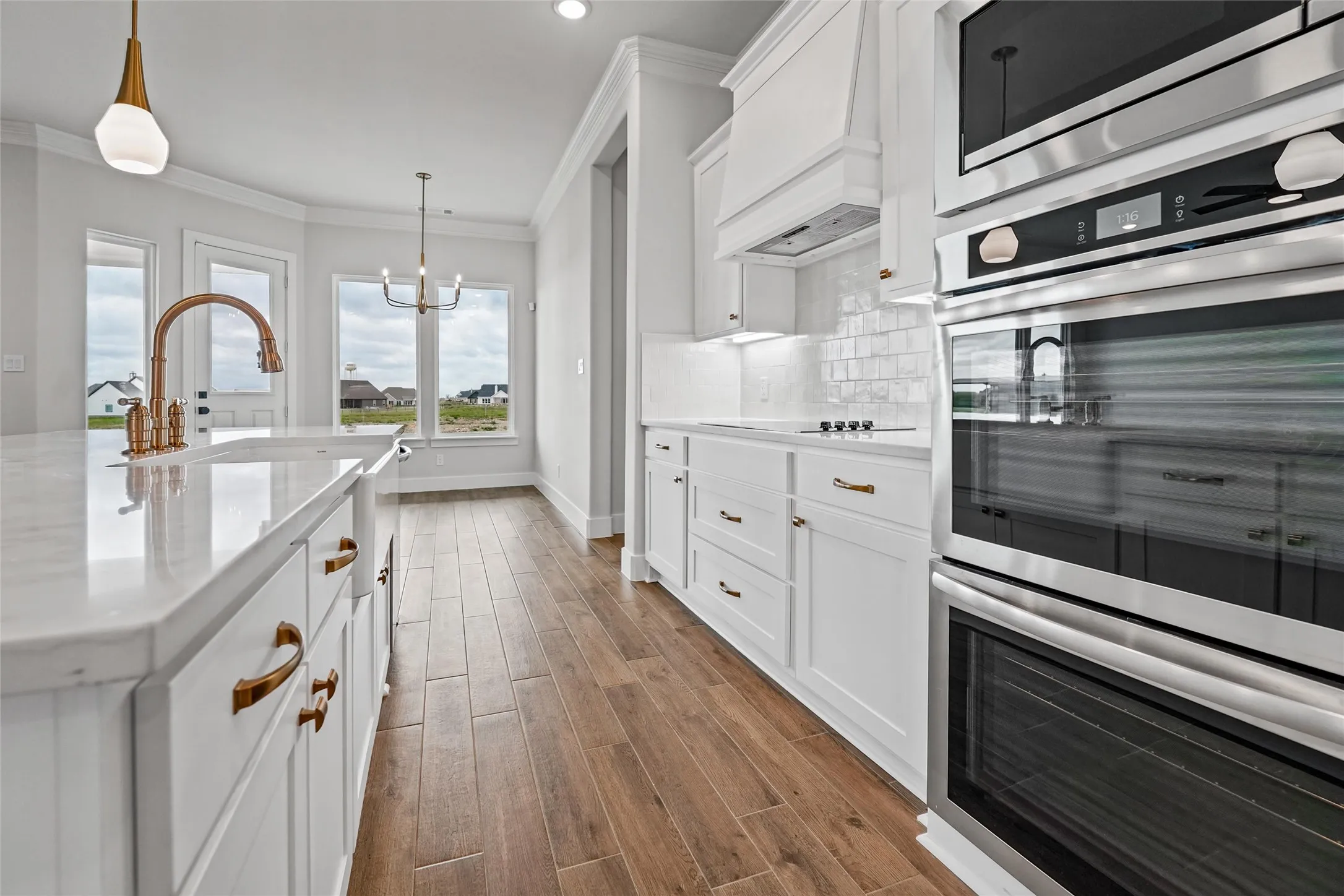 Kitchen featuring white cabinetry, built-in stainless steel appliances, wood-finish flooring, and light countertops with an integrated sink