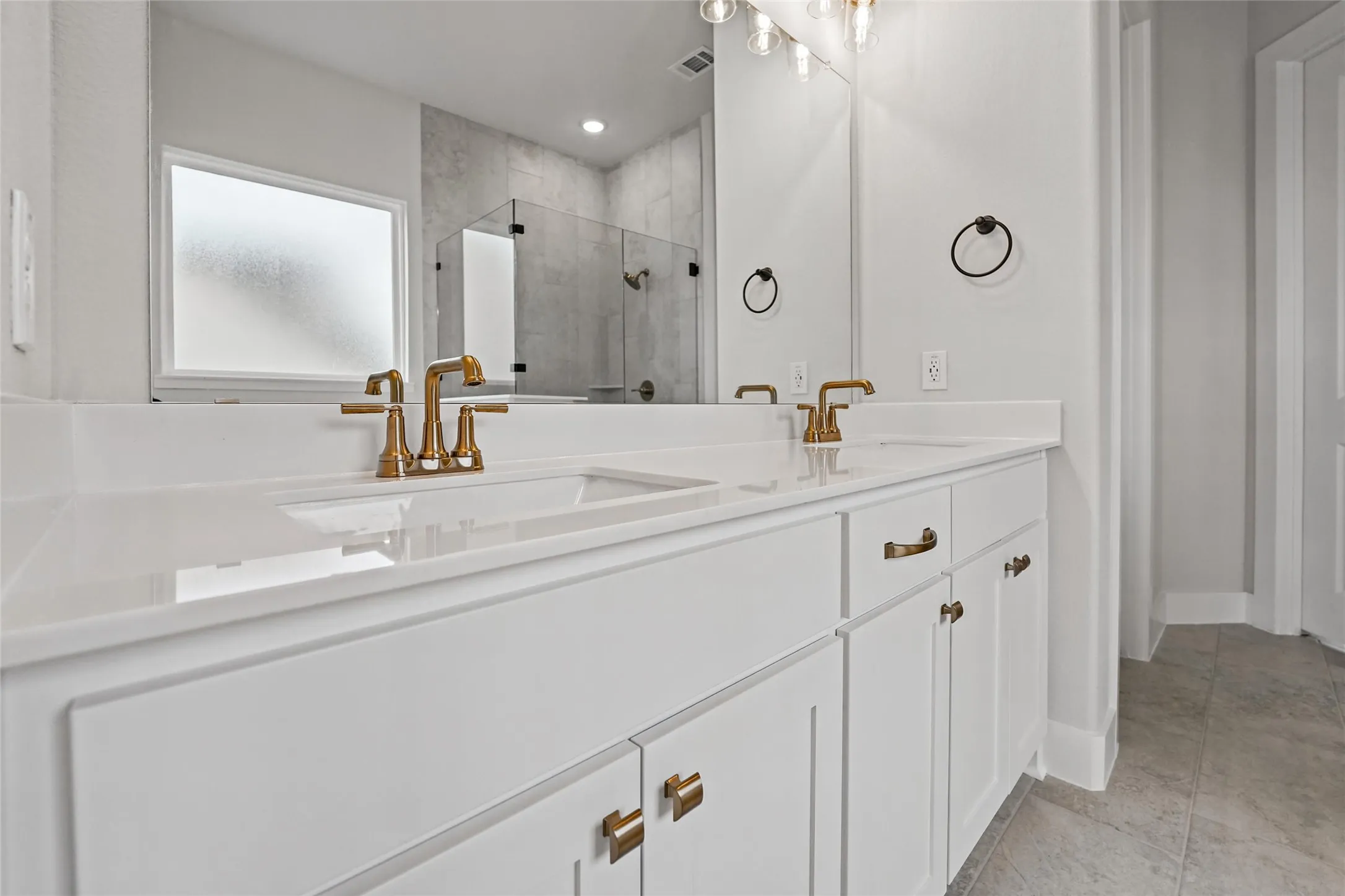 Dual vanity with white cabinetry, gold-tone hardware, and integrated rectangular sinks