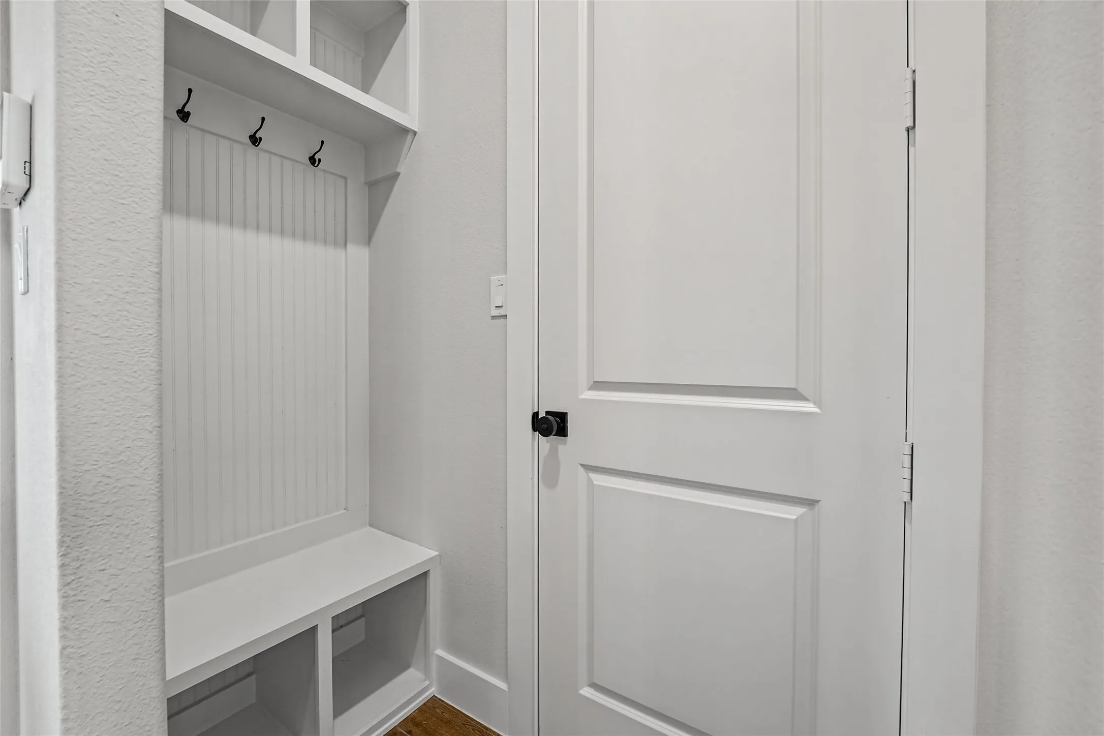 Built-in mudroom bench with cubby storage, beadboard backing, and upper shelving