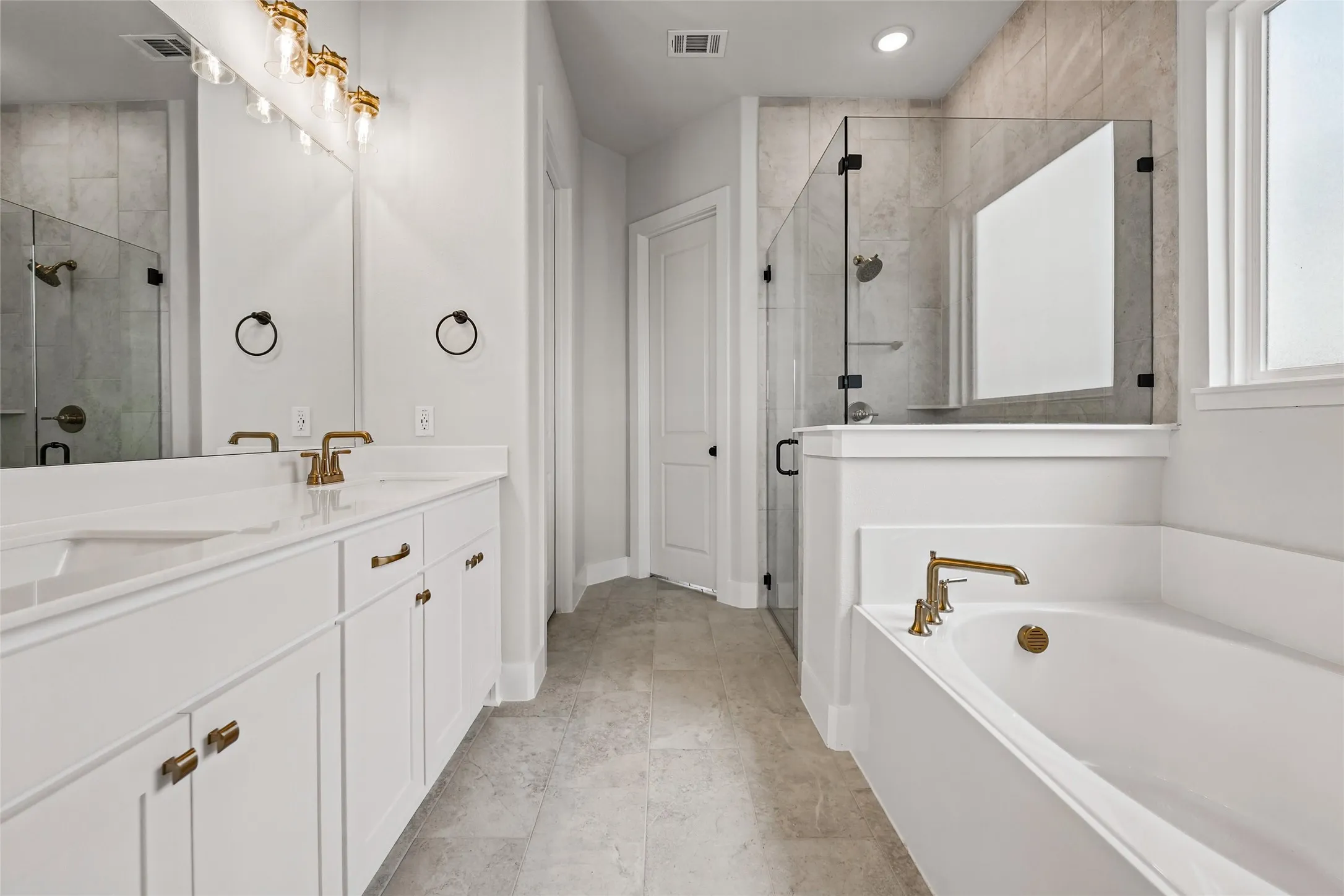 Dual vanity with white cabinetry, quartz countertops, and brass fixtures