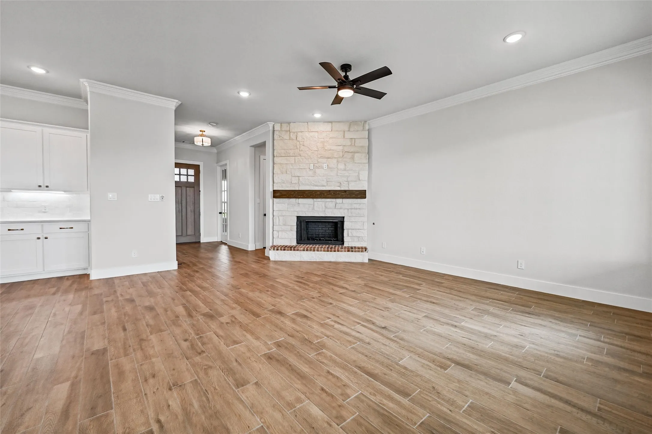 Wood-finish flooring throughout, featuring a stone-clad fireplace with a wood mantle