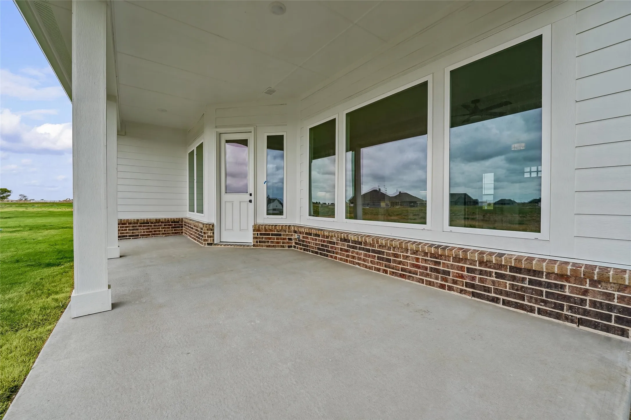 Covered concrete patio with white columns and a white paneled ceiling