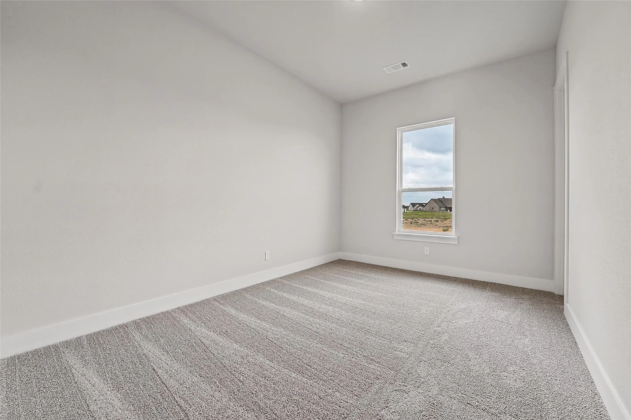 Neutral wall paint, light-toned patterned carpet, a single window, and white trim