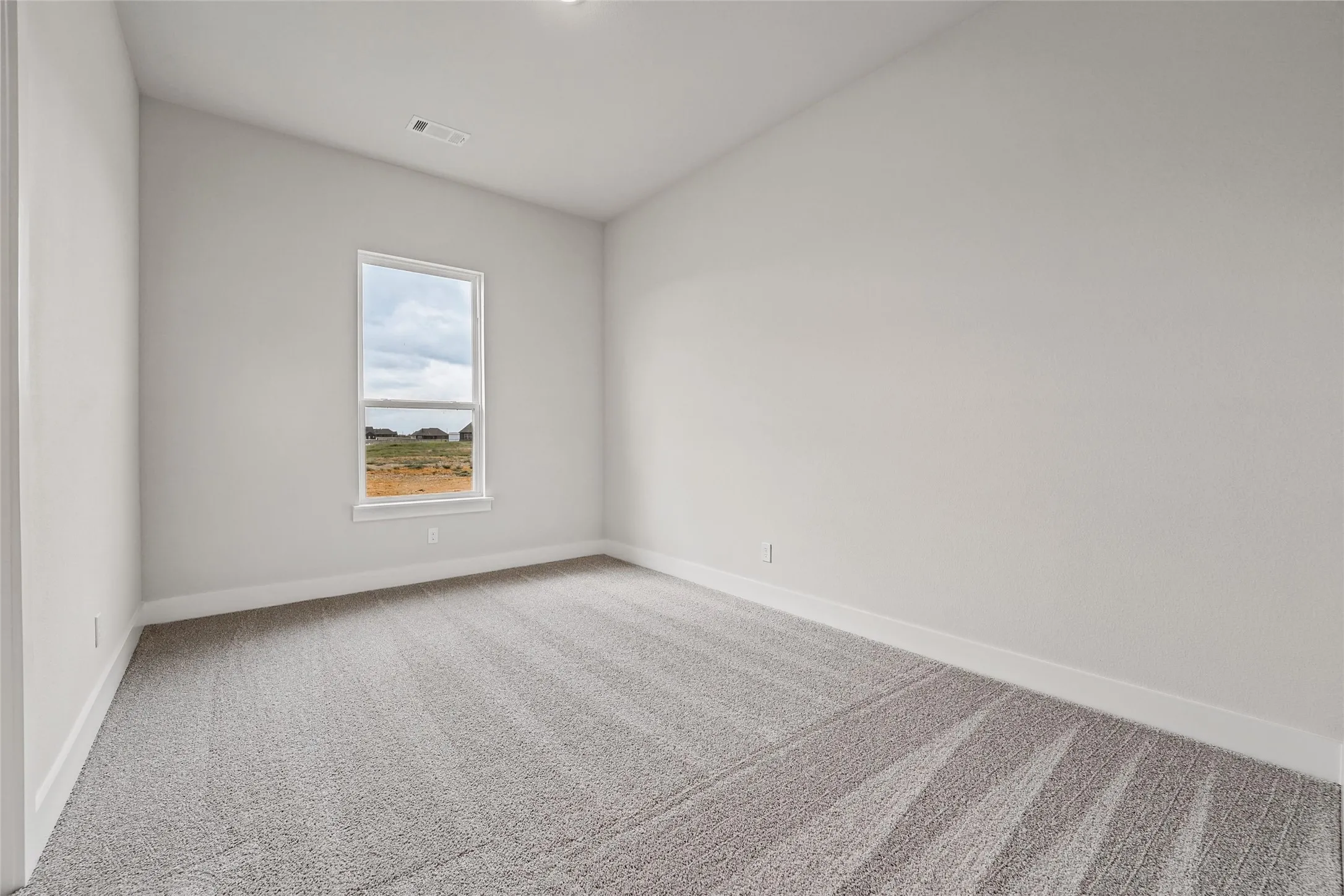 Vaulted ceiling, gray carpeting, neutral wall paint, recessed lighting, and a single window