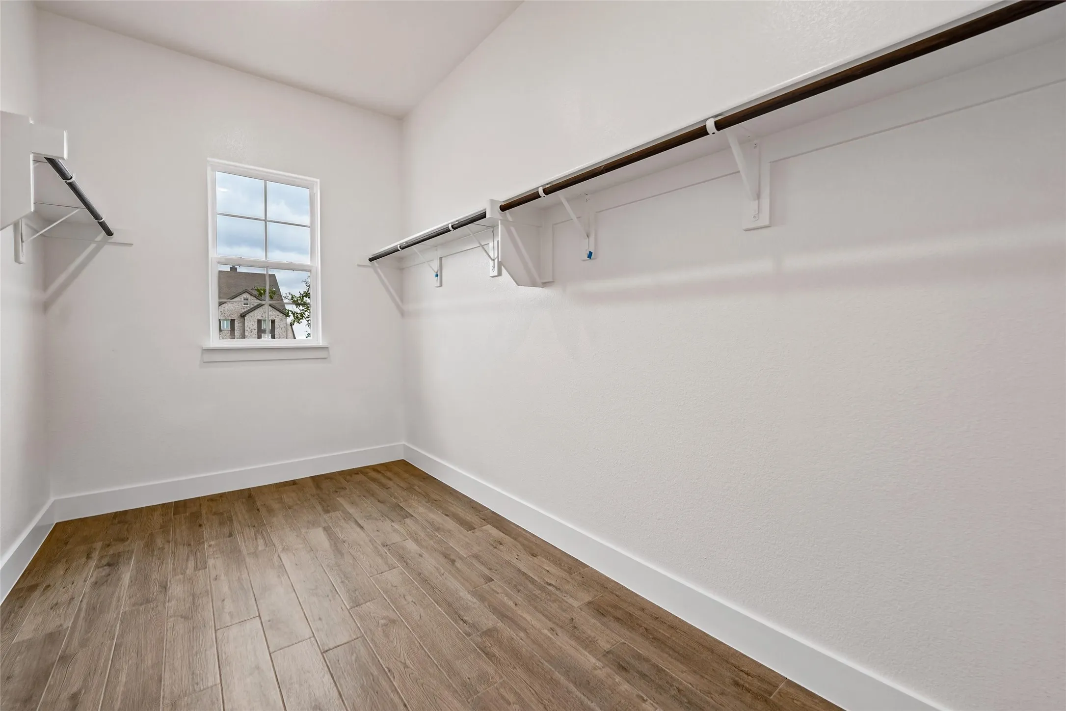 Wood-finish flooring, white walls, built-in shelving, and a single window