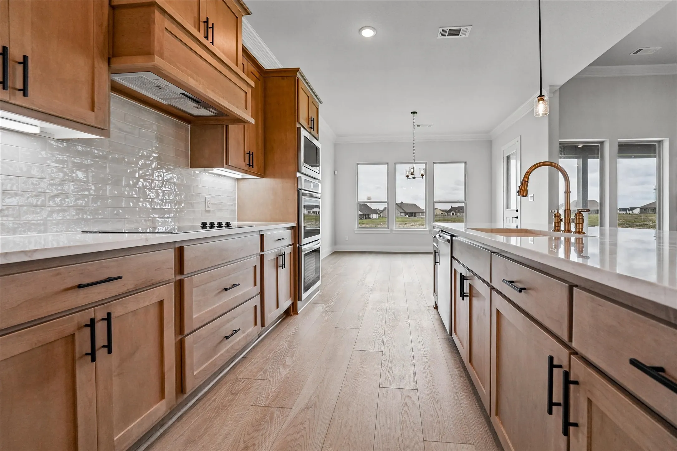 Light wood-finish flooring with perimeter cabinetry and an island featuring black hardware