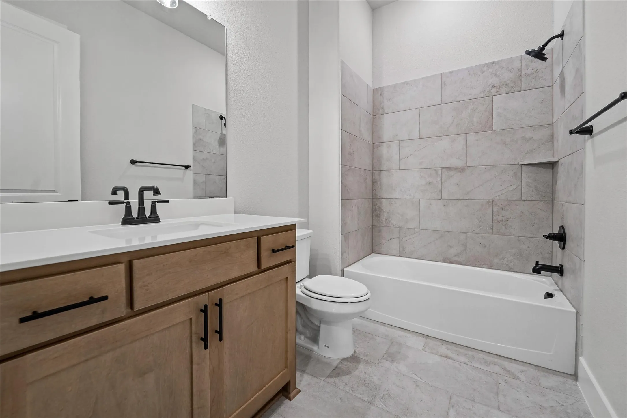 Wood-finish vanity with matte black hardware and white countertop
