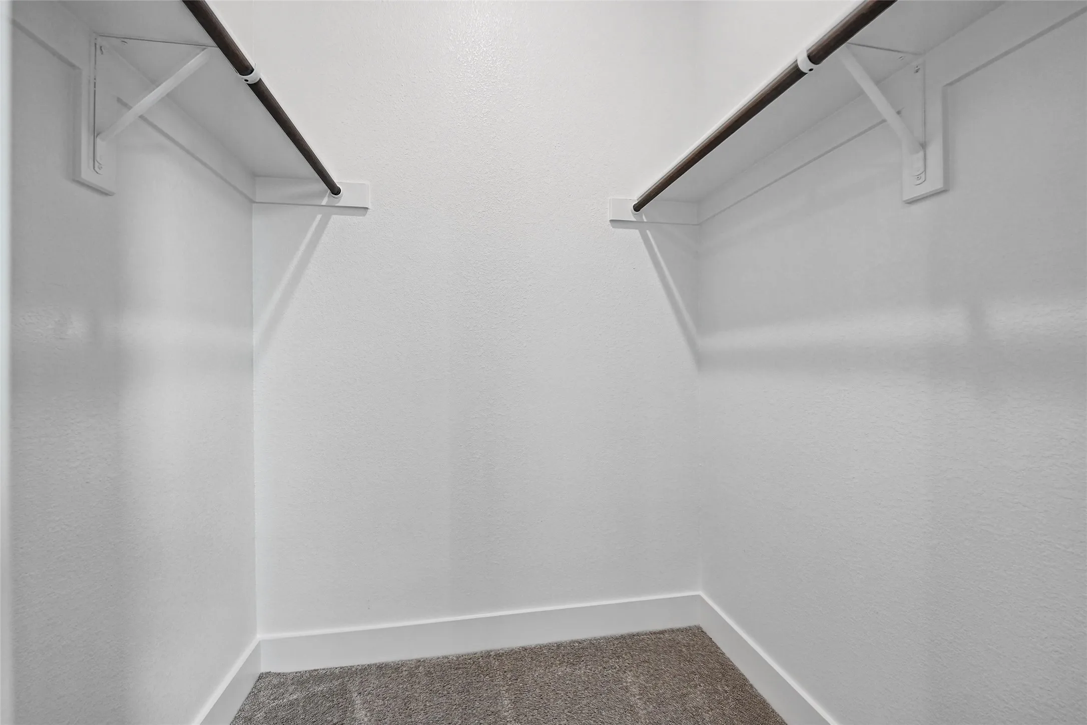 Carpeted flooring, white walls, and dual hanging rods