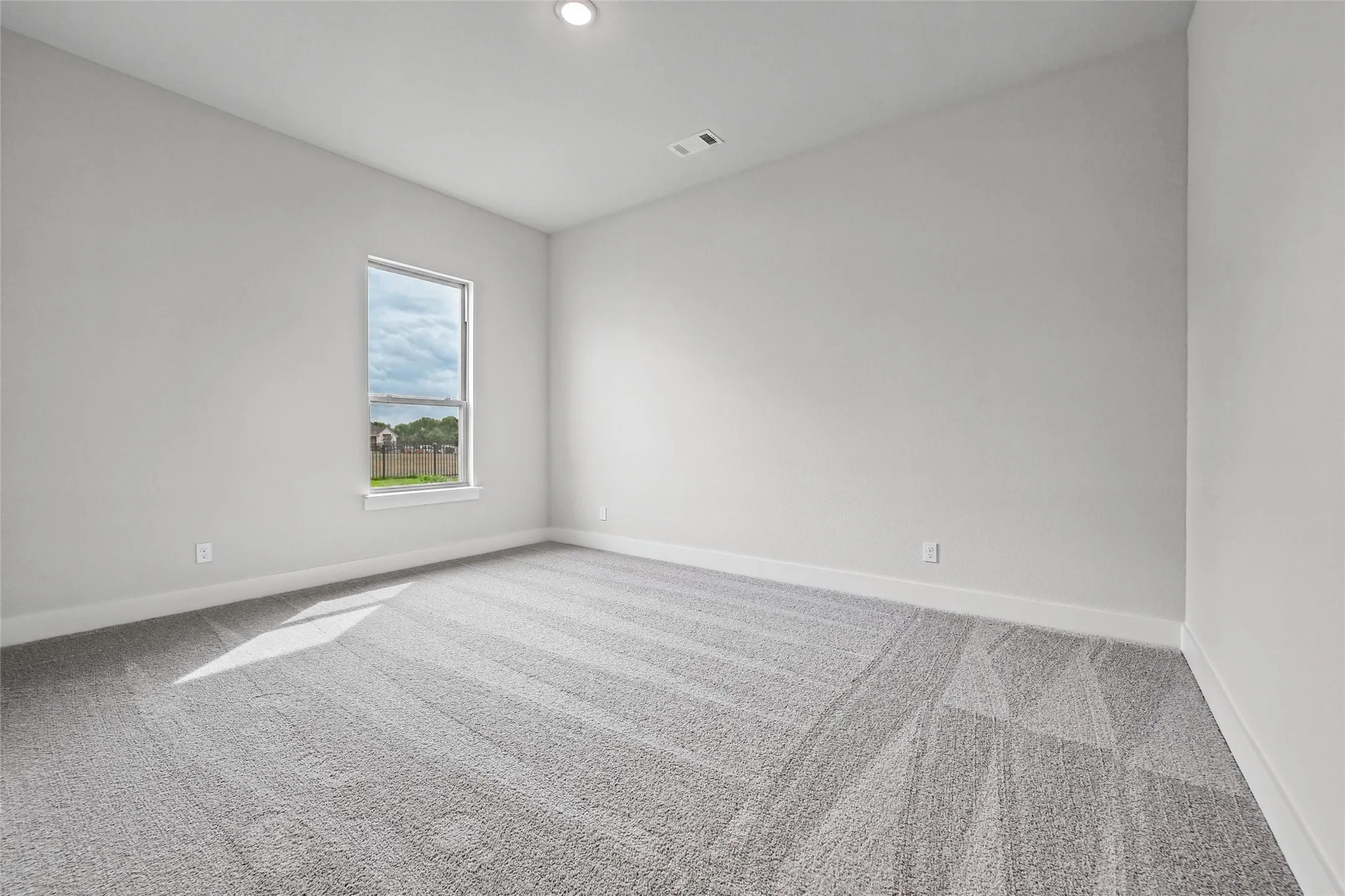 Neutral wall paint, recessed lighting, double-hung window, and neutral carpeting
