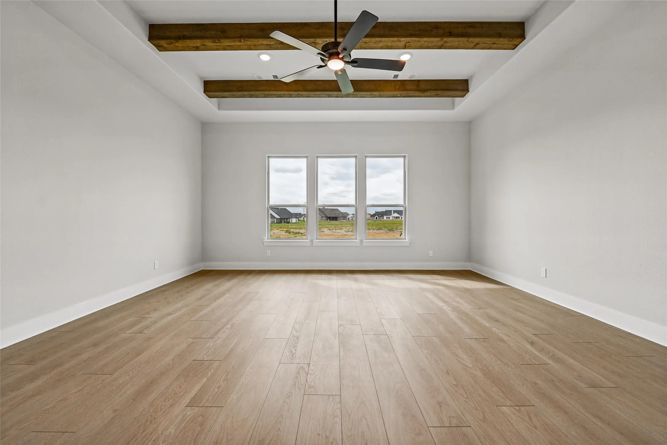 Wood-finish flooring, recessed lighting, ceiling fan, coffered ceiling with exposed wood beams, and three rectangular windows