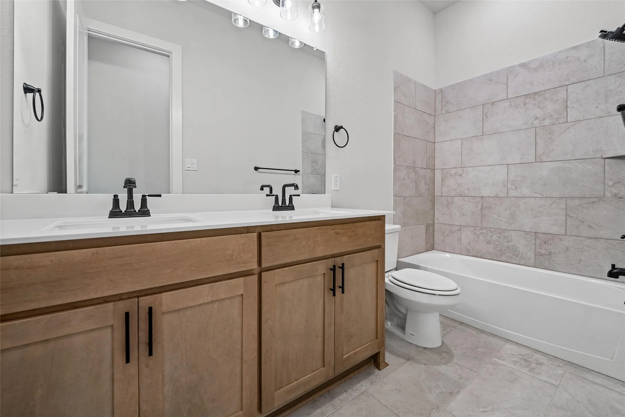 Dual vanity with undermount sinks, wood-finish cabinetry, and matte black fixtures
