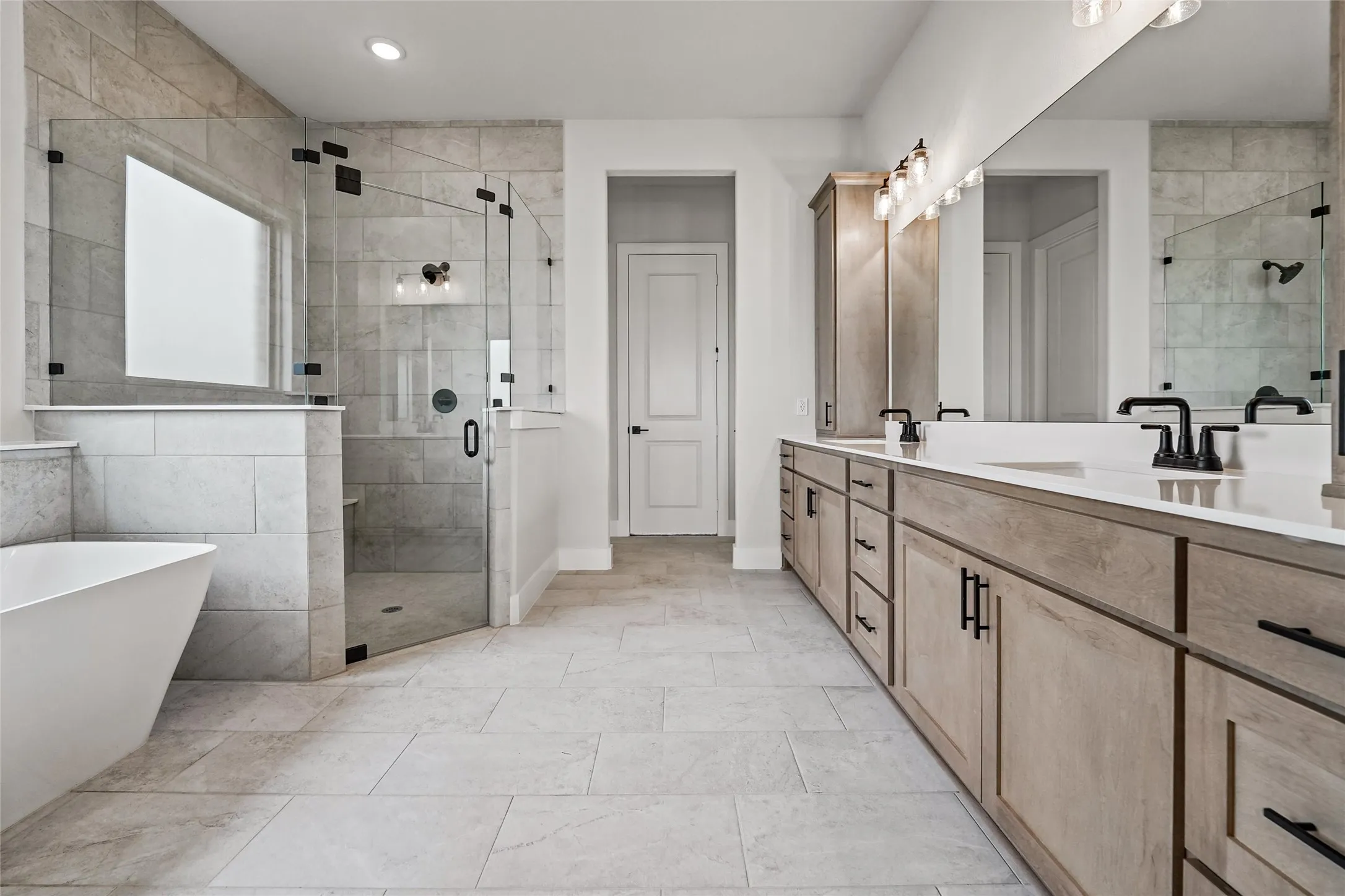 Dual vanity with light wood-finish cabinetry, white countertops, and matte black hardware