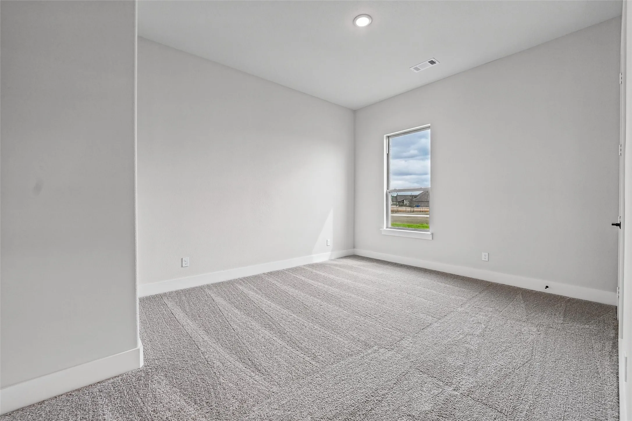Neutral paint palette, recessed lighting, window offering natural light, and gray patterned carpeting