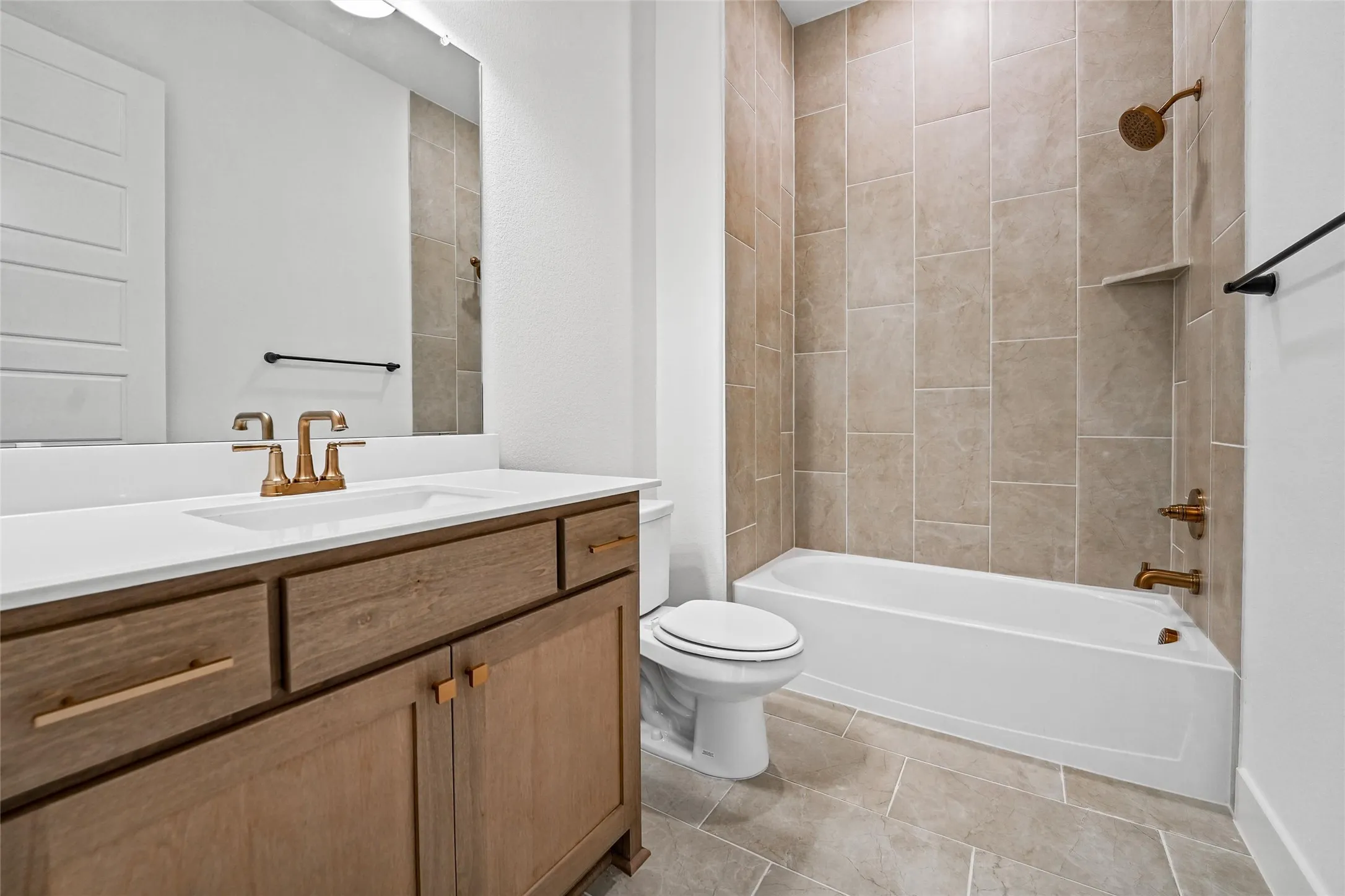 Wood-finish vanity with white countertop, undermount sink, and brass-finish fixtures