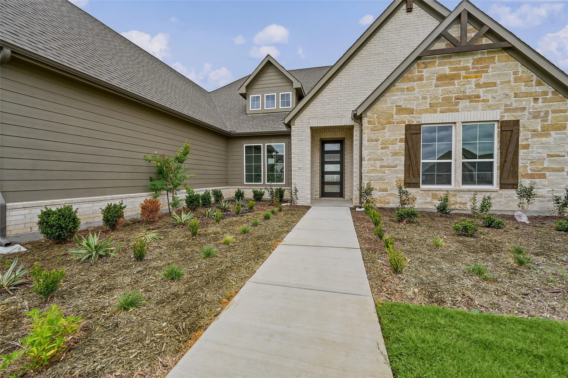 Curb appeal features stone veneer, composite siding, and wood-toned shutters