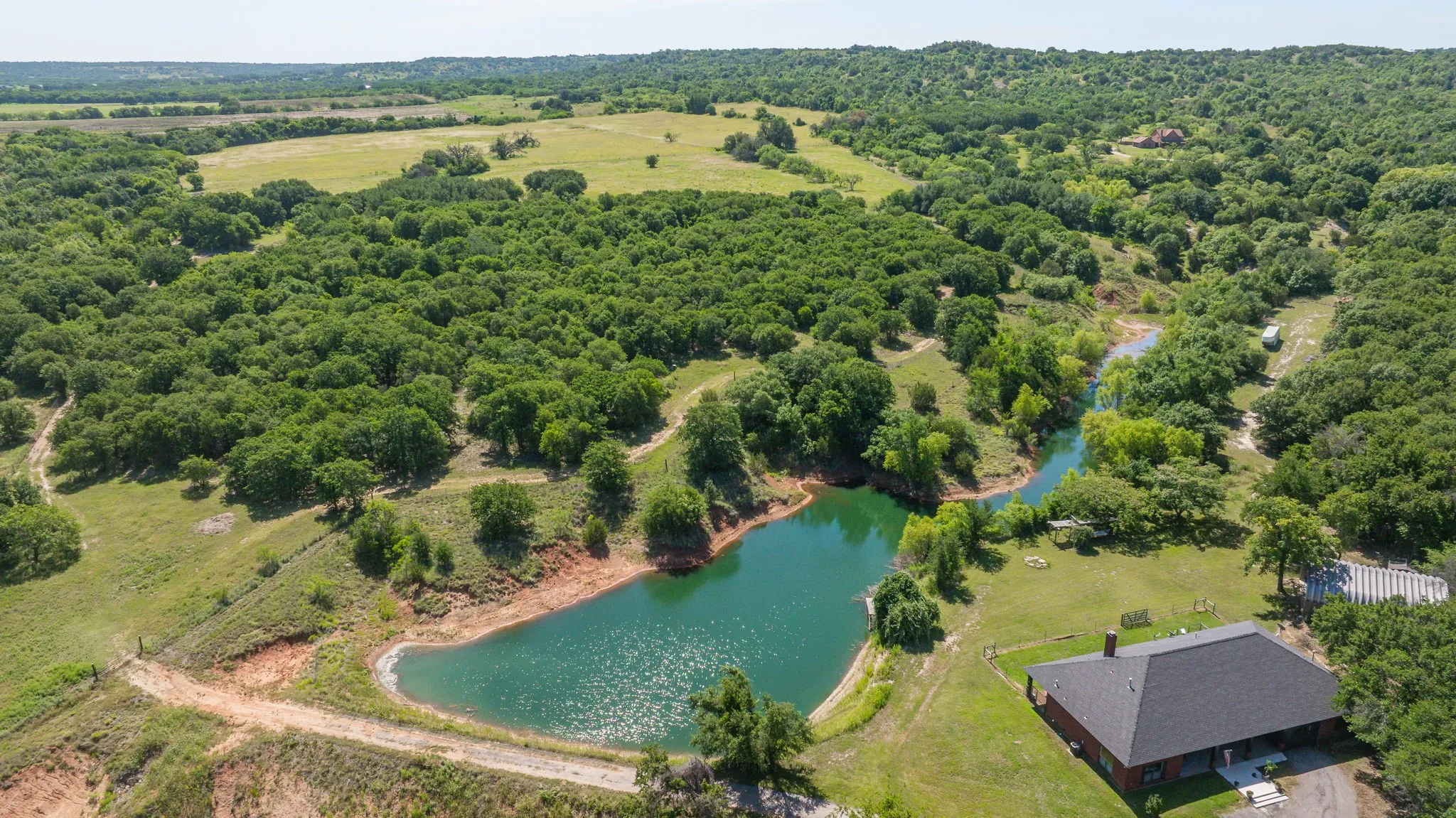 Expansive rural landscape featuring a private pond, winding creek, and abundant mature trees