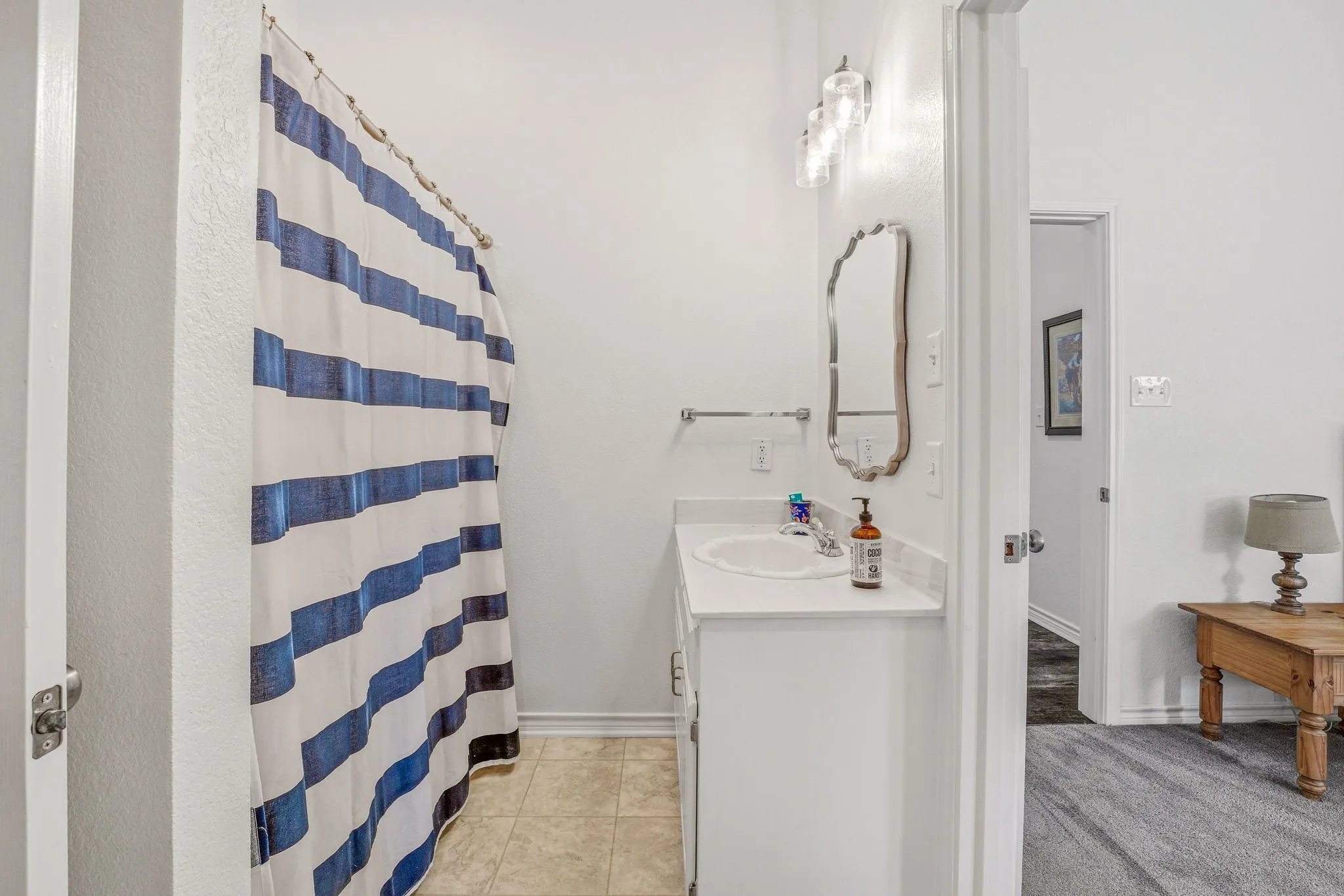 Bathroom featuring a single vanity with a white countertop and integrated sink, a wall-mounted mirror, and decorative light fixture