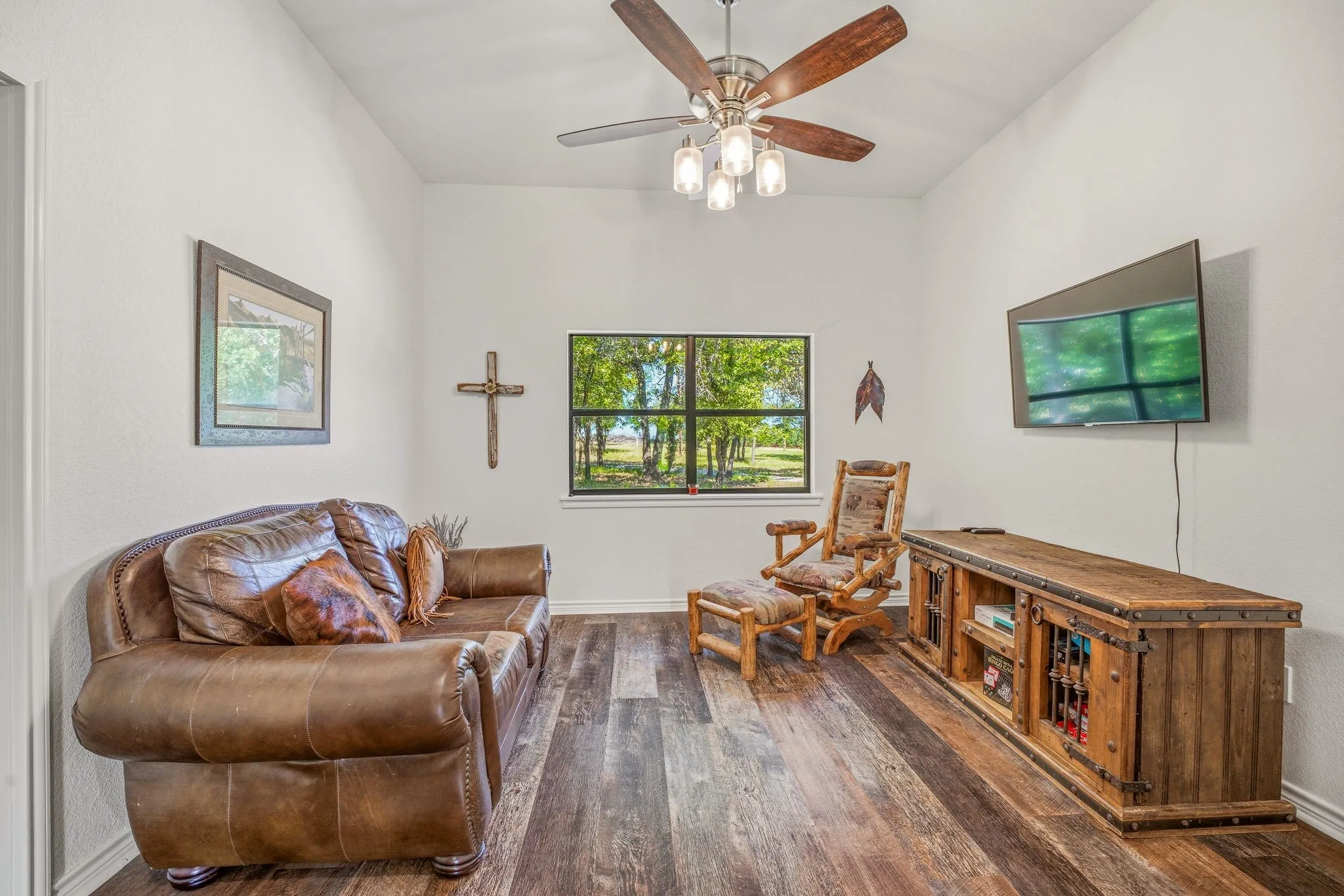 Vaulted ceiling with a ceiling fan, wood-finish flooring, and a window with outdoor scenery