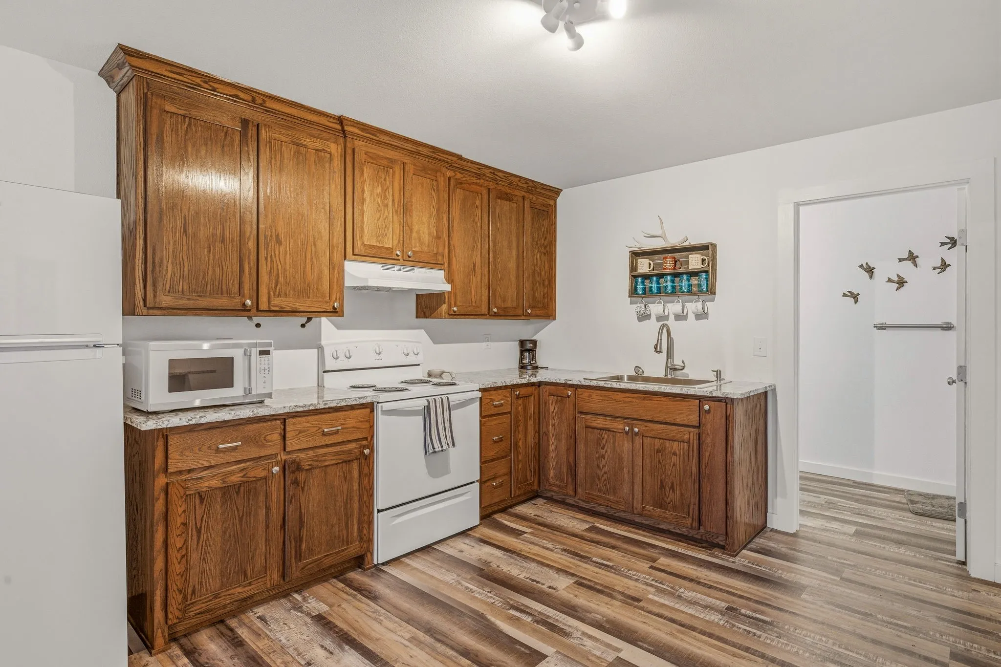 Kitchen featuring wood-finish cabinetry, white appliances, and light-toned countertops