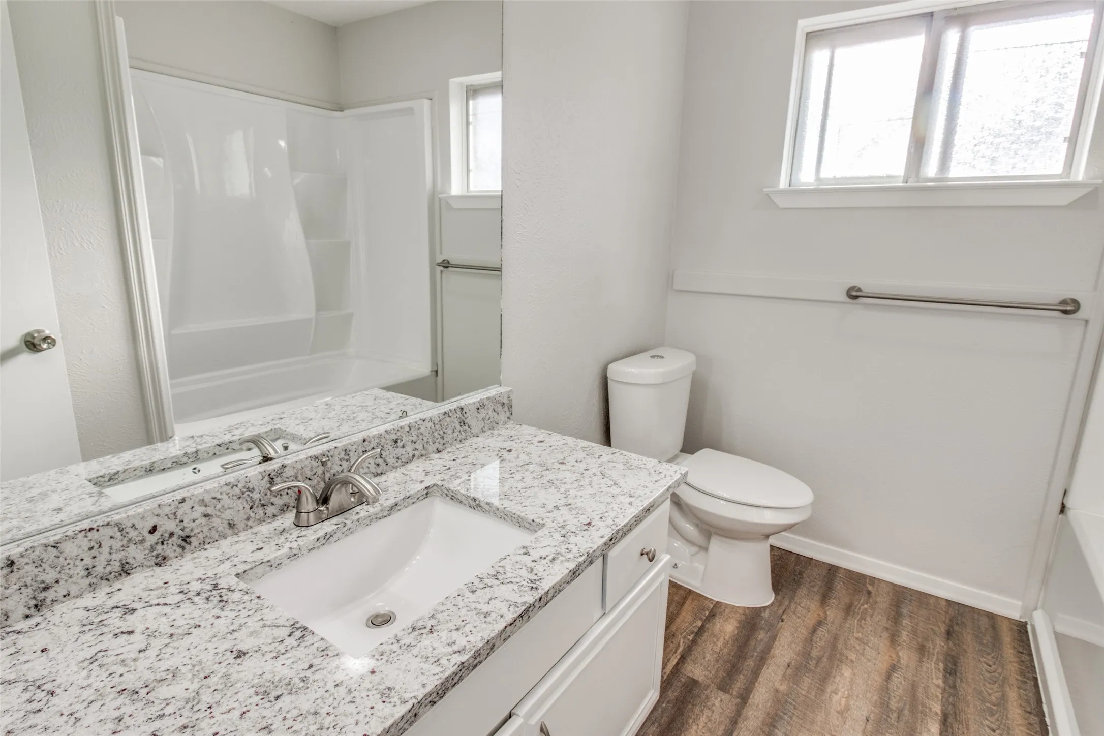 Bathroom featuring a white vanity with a speckled countertop, undermount sink, and brushed nickel faucet