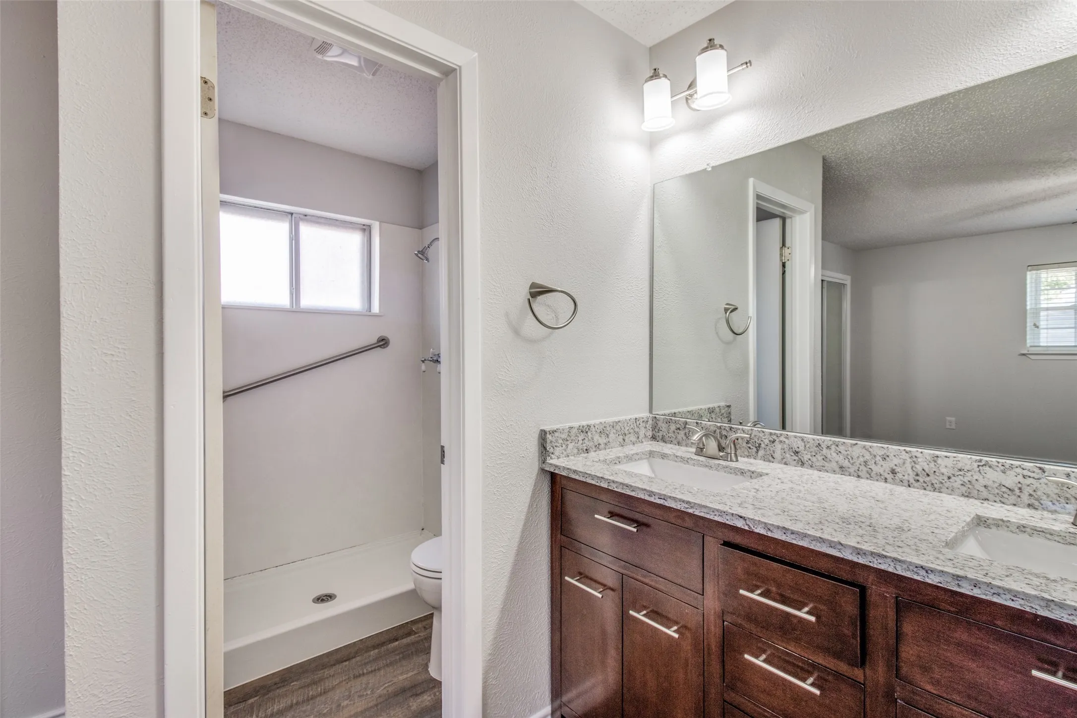 Dual vanity with a speckled countertop, undermount sinks, and dark wood cabinetry
