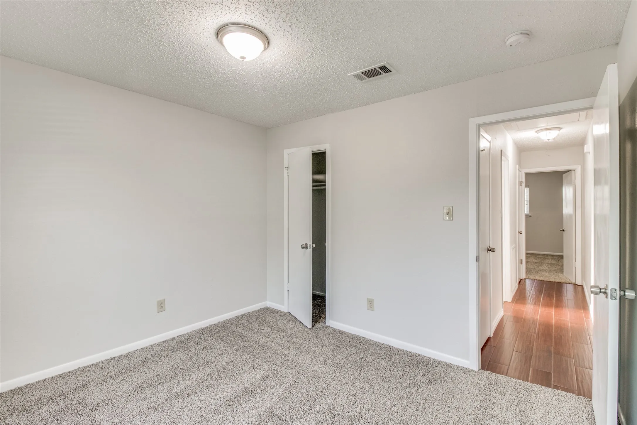 Carpeted room with white walls, a flush-mount ceiling light, and baseboard trim