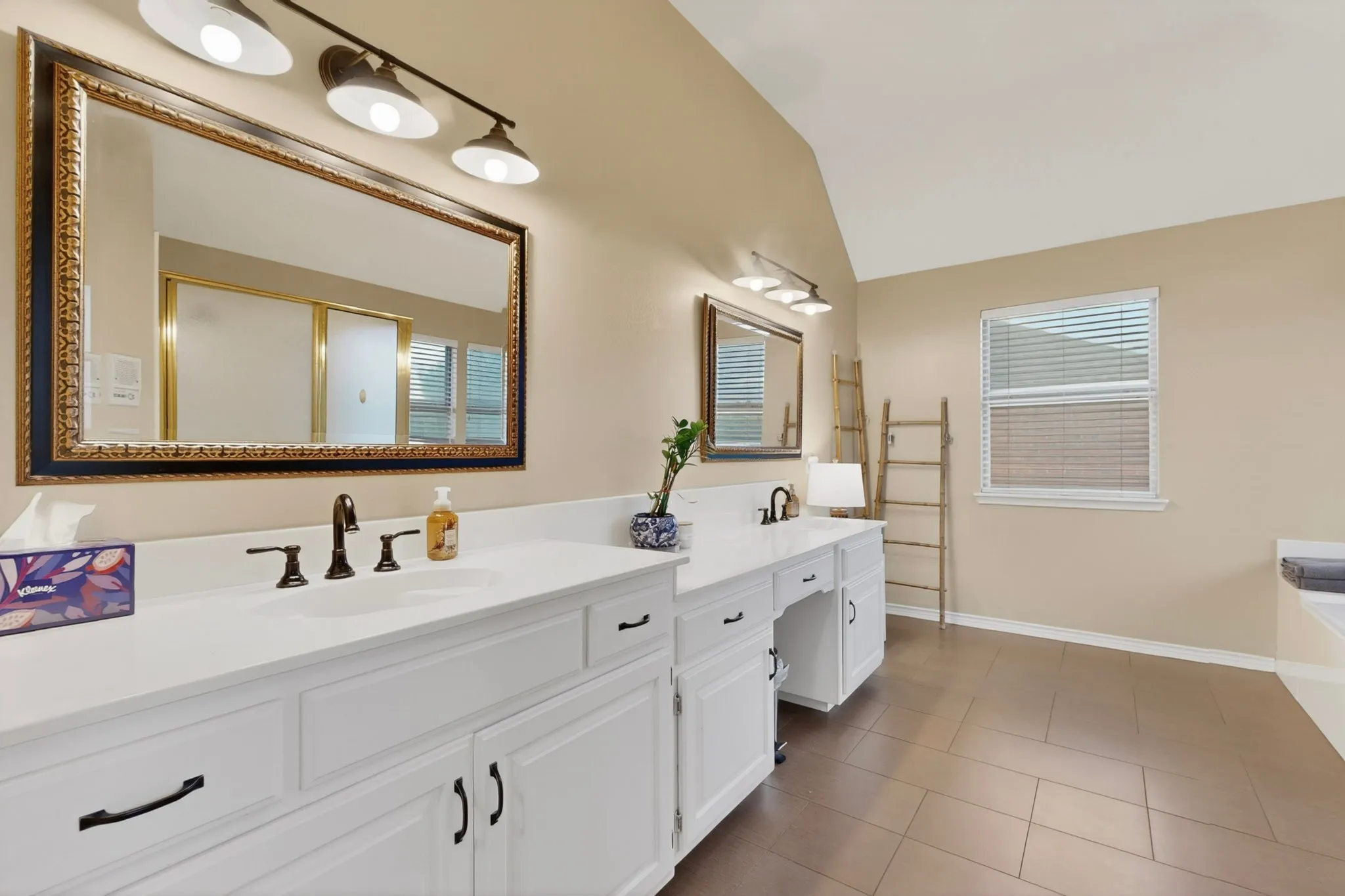 Double vanity with white cabinetry, matte black hardware, and an ornate framed mirror