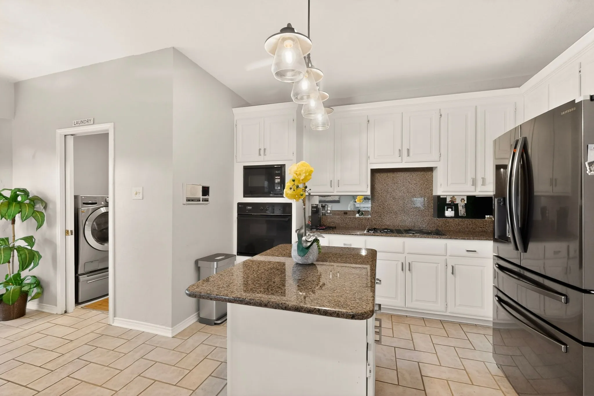 Kitchen featuring white cabinetry, built-in appliances, a central island with a granite countertop, and tiled flooring