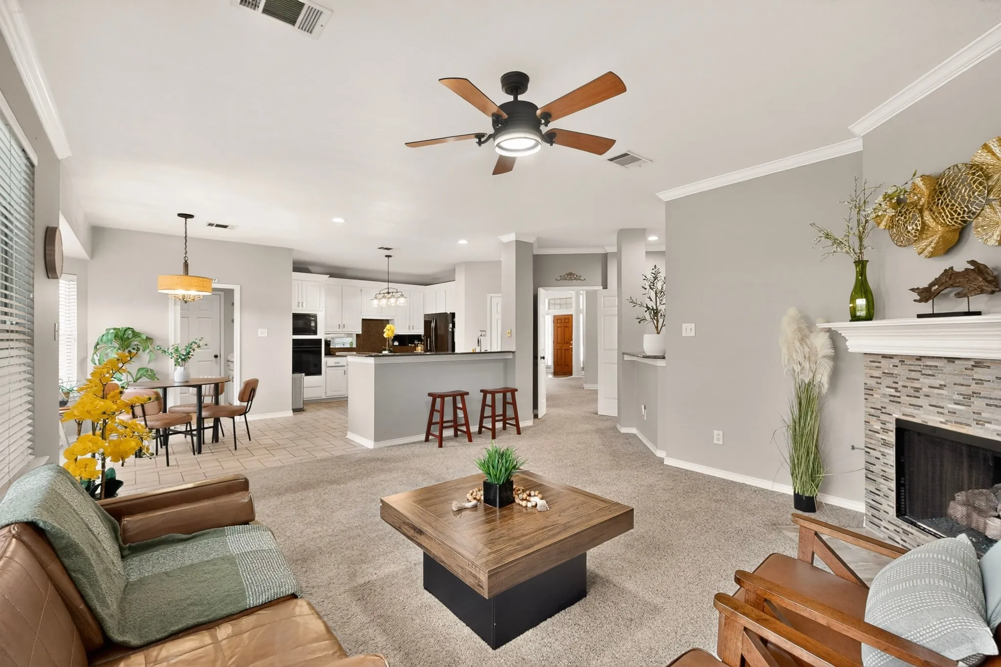 Spacious living area featuring carpet flooring, a ceiling fan with integrated lighting, and crown molding