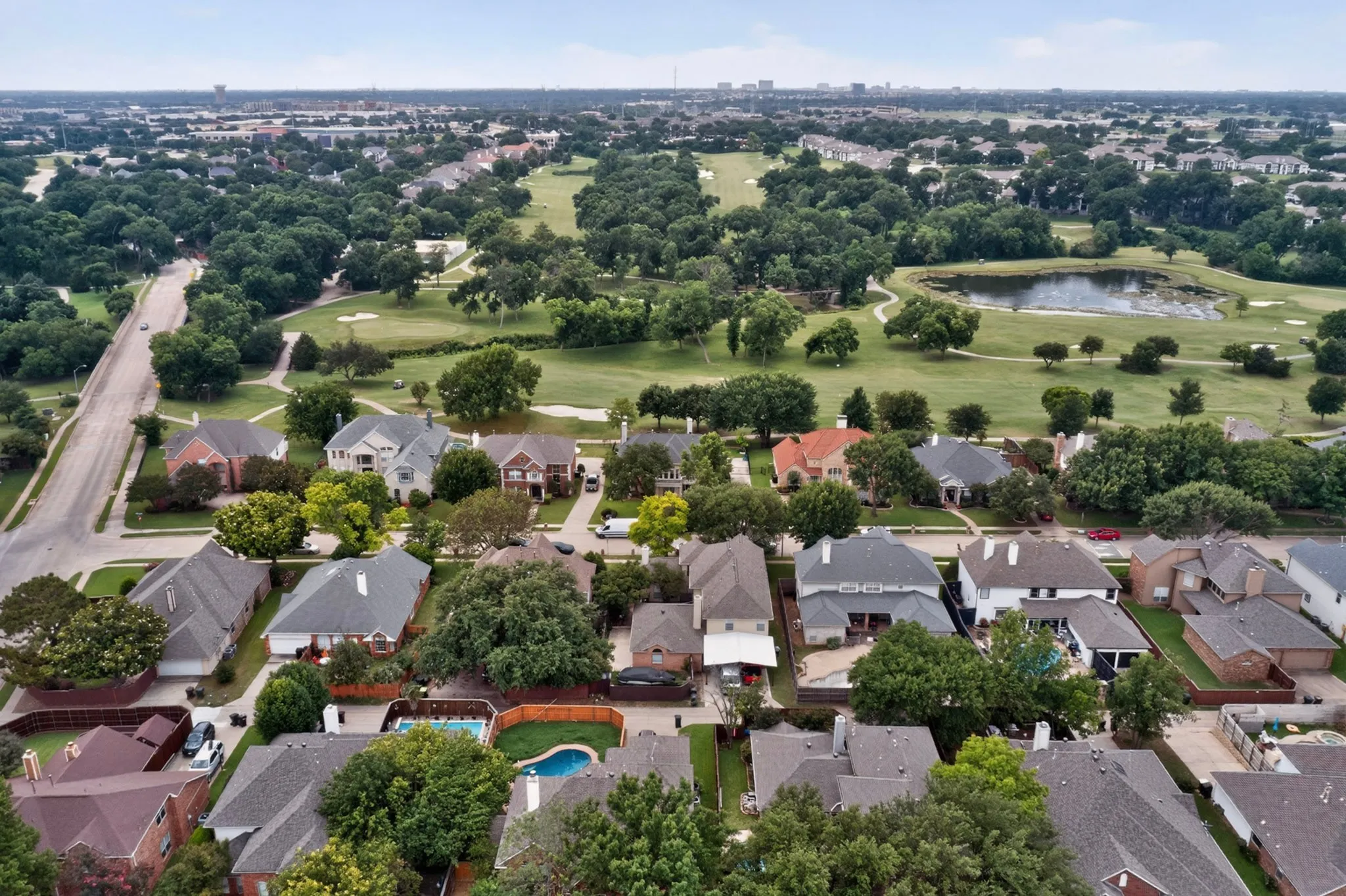 Established residential neighborhood featuring mature trees and a golf course with a pond