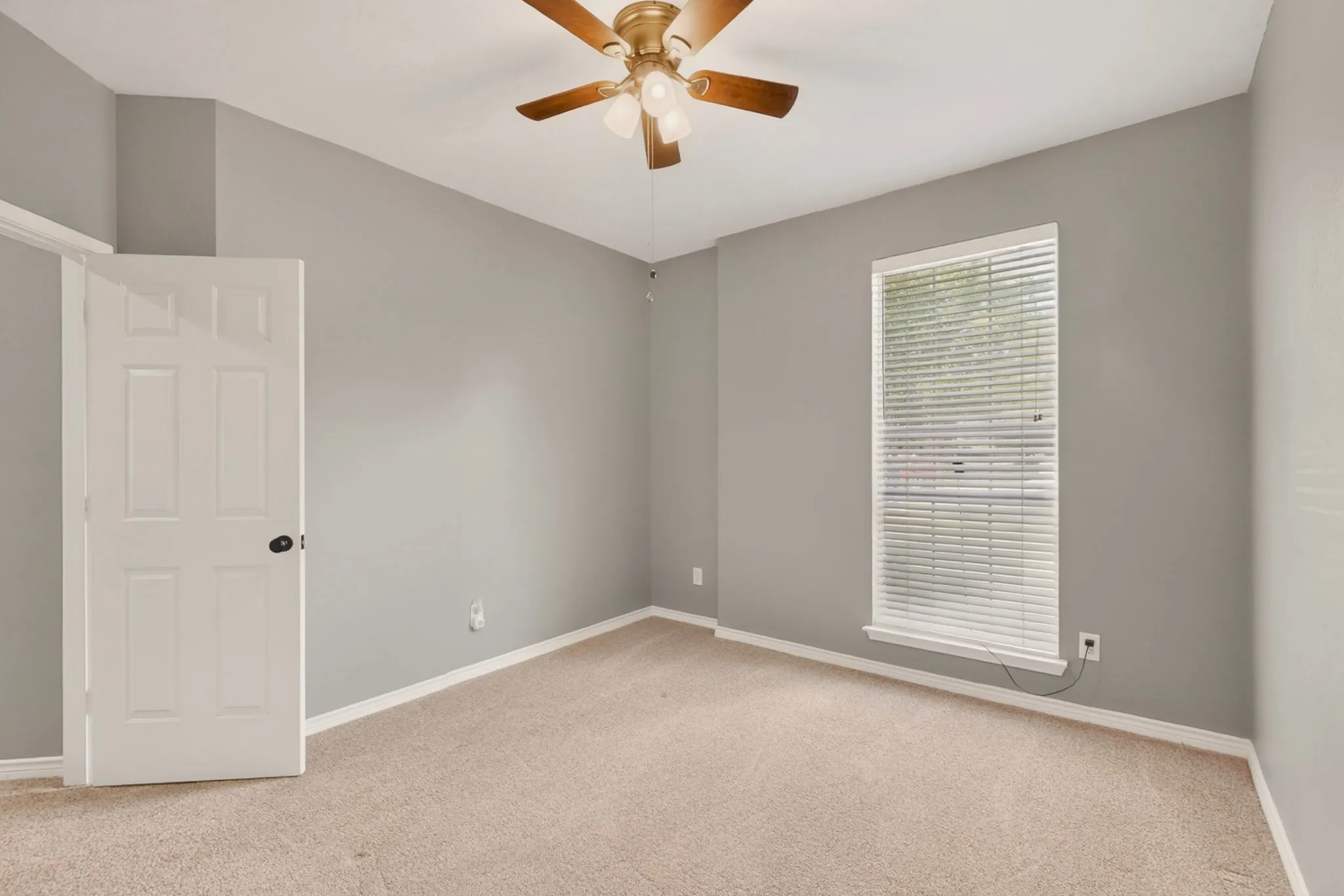 Neutral-toned room featuring carpet flooring, a window with blinds, and a ceiling fan with light fixture