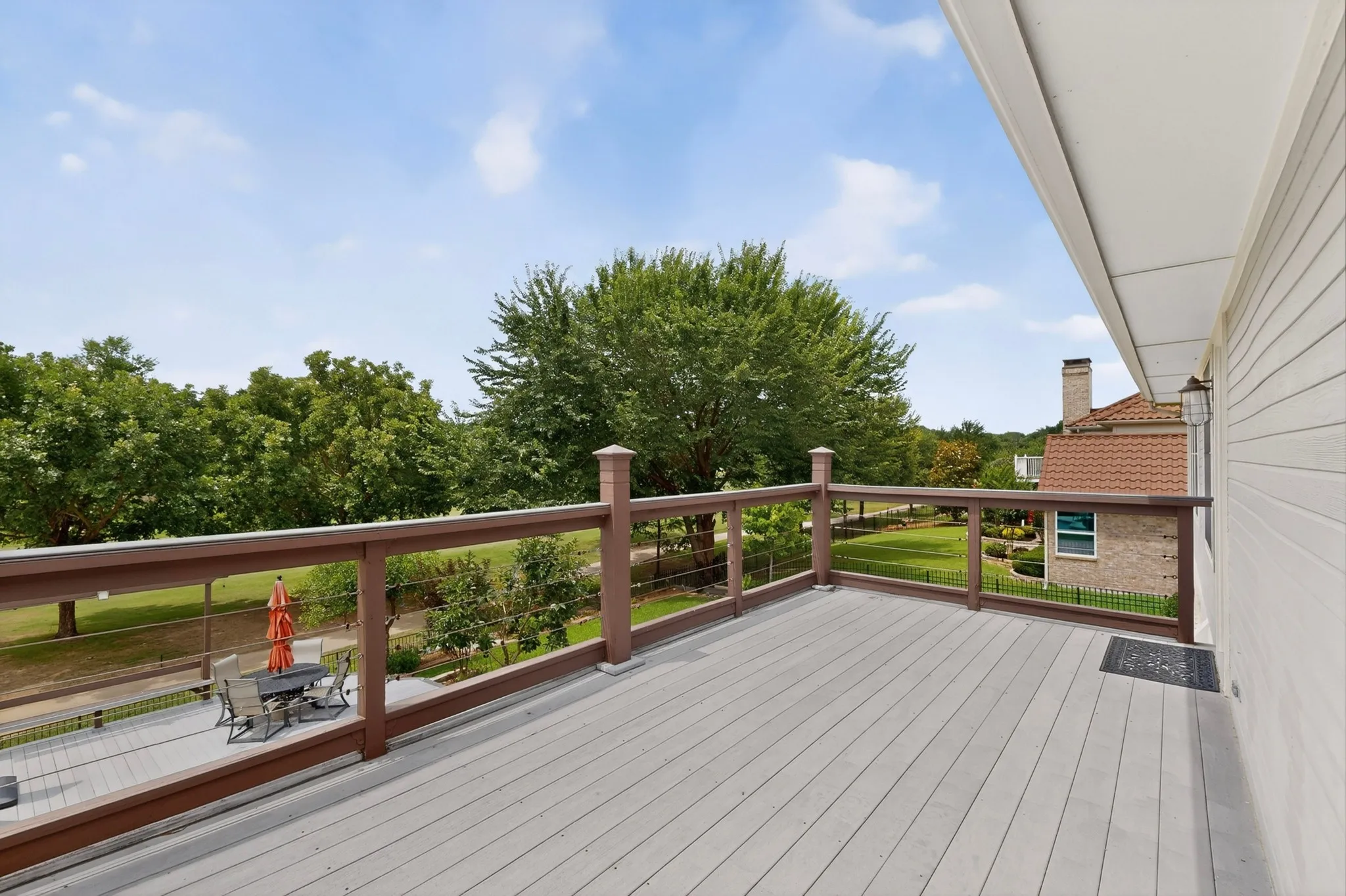 Expansive outdoor deck featuring wood-finish flooring and a cable railing system