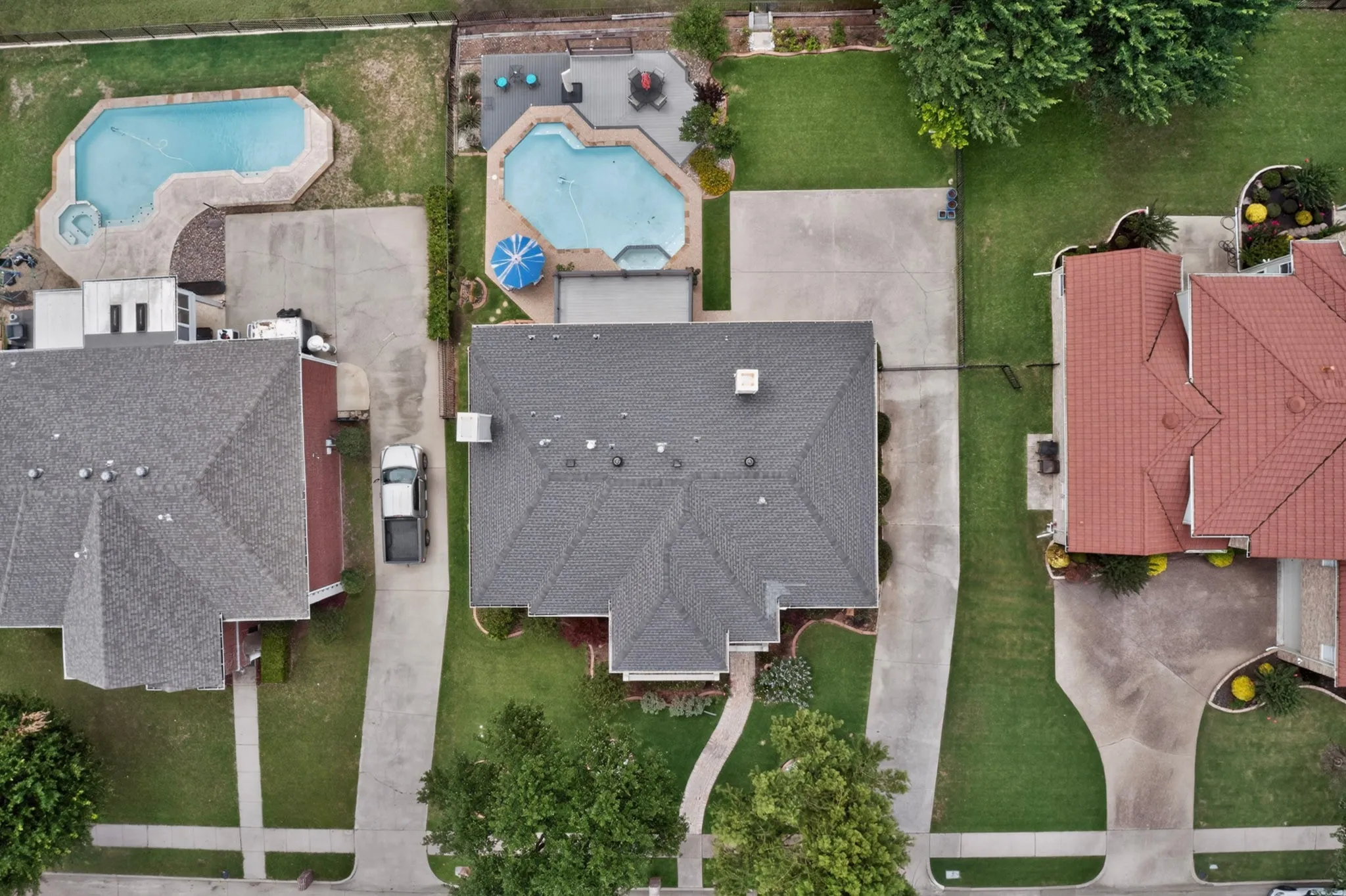 Residential property featuring a grey shingle roof, concrete driveway, and established green lawn