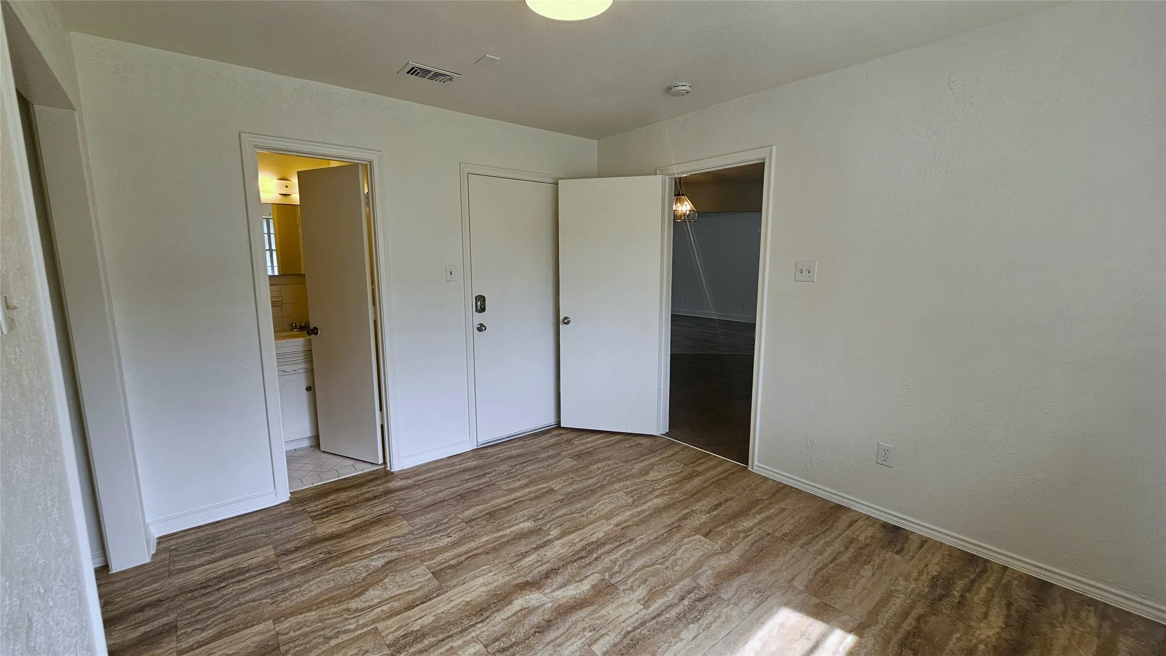 Unfurnished bedroom featuring wood finished floors, baseboards, aBedroom 4 featuring luxury vinyl tyle floors, window view of side yard and ensuite full bathroom and direct access to back yard. closet, and ensuite bath