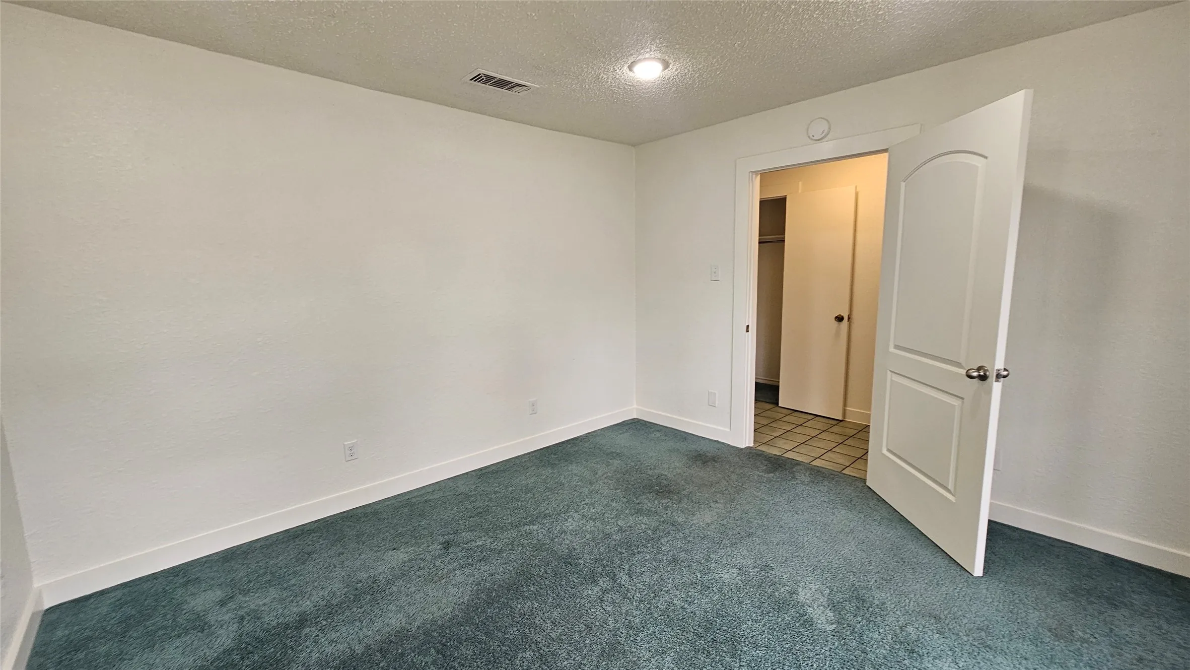 Bedroom 2 with blue carpet, a textured ceiling, and baseboards